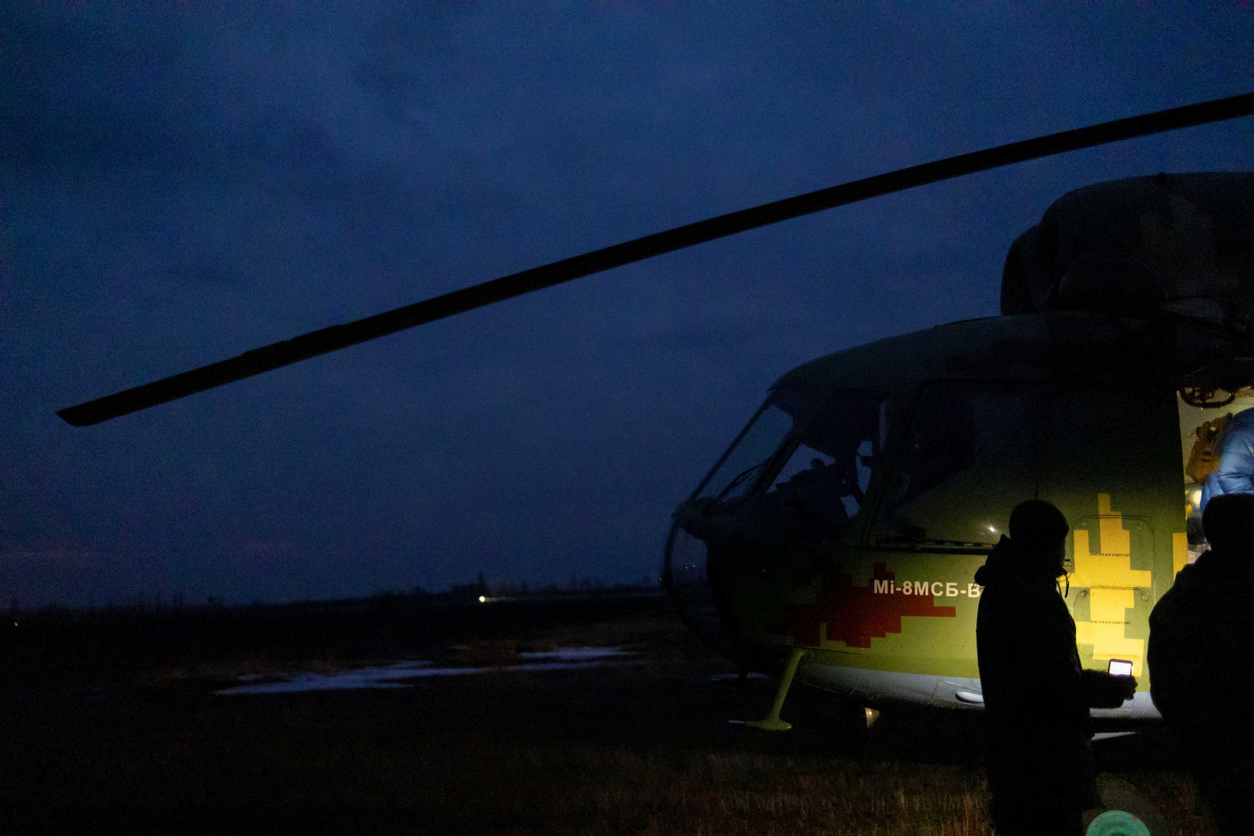 A service member of the Ukrainian armed forces holds a flashlight as passengers arrive at an airfield near Stanytsia Luhanska, in the Luhansk region, Ukraine, February 17, 2022. REUTERS