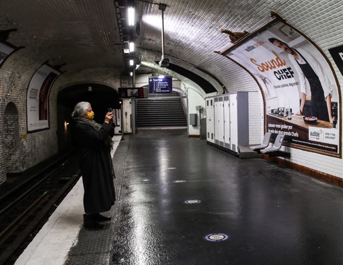 epa08912886 A passenger wearing a face mask, takes a picture inside Bonne Nouvelle metro station after employees from RATP Group added a phrase under the name of the station that reads 'Good news, 2020 is finished’ in Paris, France, 31 December 2020. To curb the spread of the coronavirus Covid-19 pandemic, a national curfew between 8 p.m. and 6 a.m. has been in place since 15 December 2020. All street gatherings or celebrations for New Year's Eve were canceled.  EPA