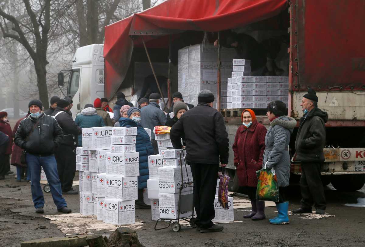 FILE PHOTO: Local residents gather near a cargo trailer loaded with boxes containing food and personal hygiene products during the distribution of humanitarian aid from the International Committee of the Red Cross in the rebel-controlled city of Donetsk, Ukraine, March 17, 2021. REUTERS