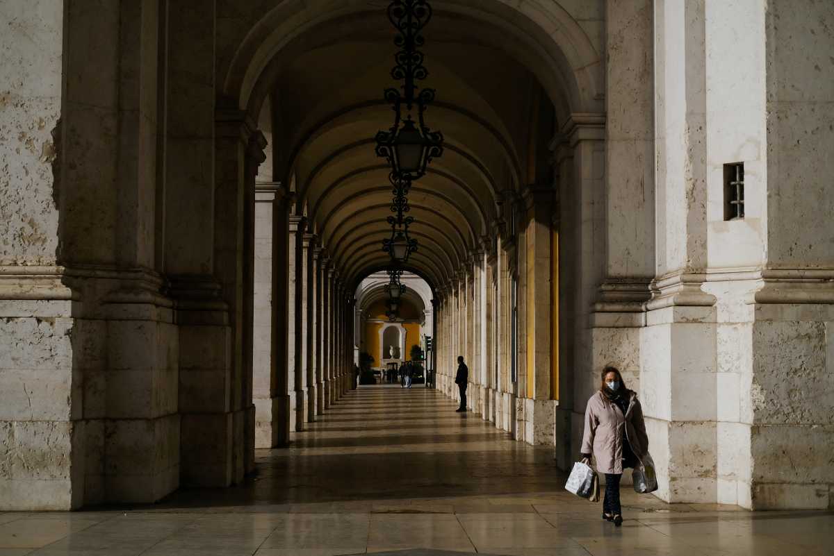 FILE PHOTO: A woman wearing a protective masks walks in Terreiro do Paco, moments before a governmental news conference to announce new coronavirus disease (COVID-19) restrictions, in Lisbon, Portugal, December 21, 2021. REUTERS