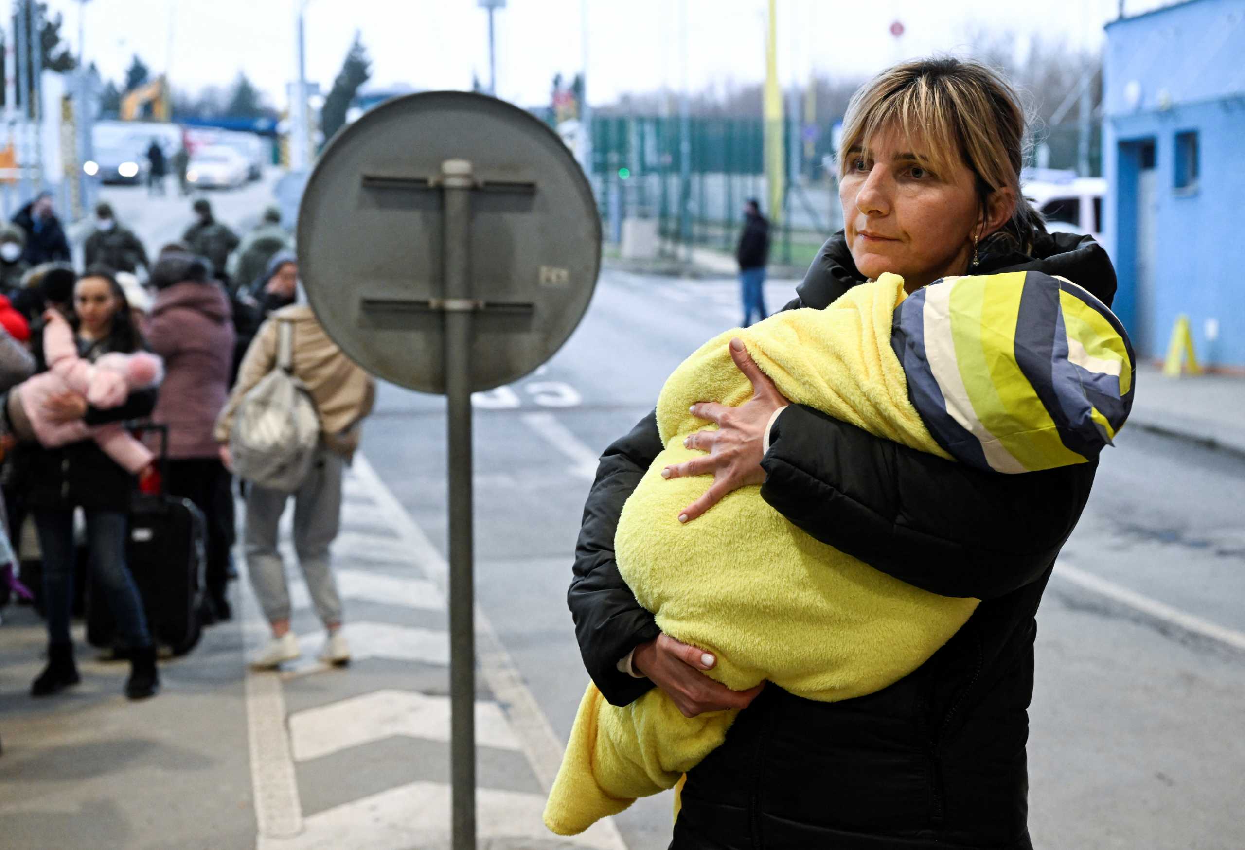 A woman carries a child on arrival to the border of Ukraine-Slovakia, after Russia launched a massive military operation against Ukraine, in Vysne Nemecke, Slovakia, February 25, 2022. REUTERS