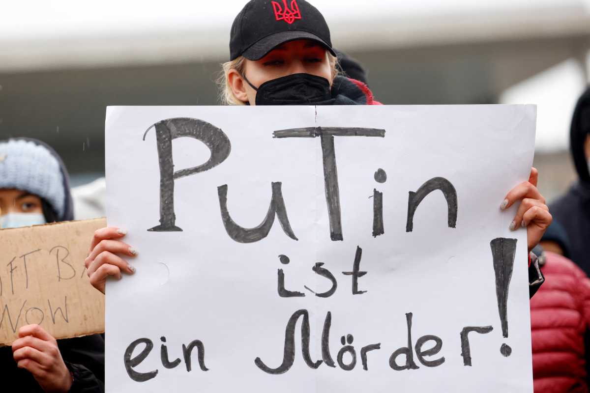 A protestor holds a sign that reads "Putin is a murderer" outside the German chancellery, after Russia launched a massive military operation against Ukraine in Berlin, Germany, February 25, 2022. REUTERS