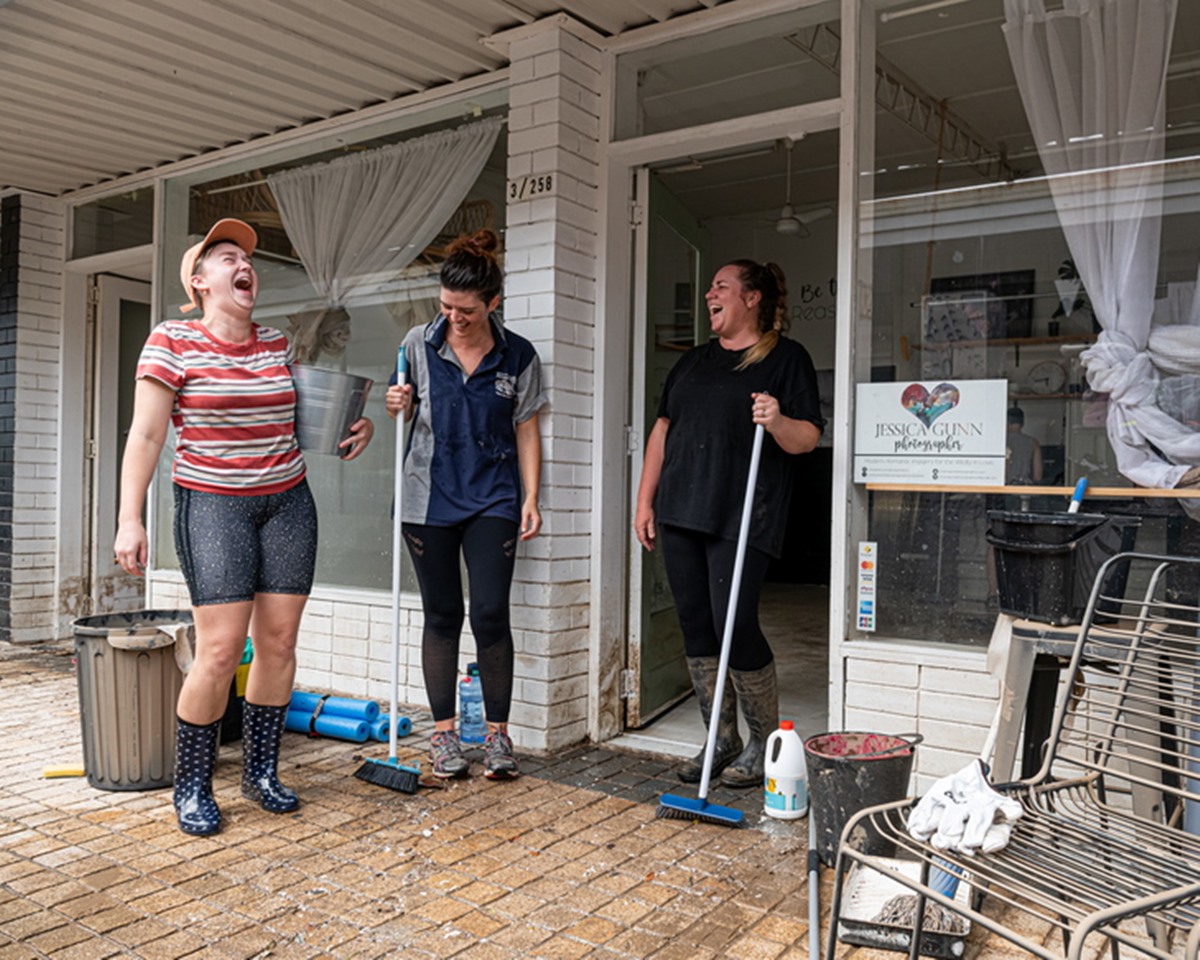 epa09677983 Brittany Robinson, Roxanne Spies and Jessica Gunn react while cleaning up damage from floodwaters in Maryborough, 220 km north of Brisbane, Australia, 11 January 2022. The regional city of Maryborough is mopping up after an underground stormwater mechanism failed, allowing floodwater to surge up through the drains. More than 30 inner-city blocks were issued with an evacuation order after the remnants of tropical cyclone Seth dumped 600mm of rain on the Wide Bay-Burnett region in two days.  EPA