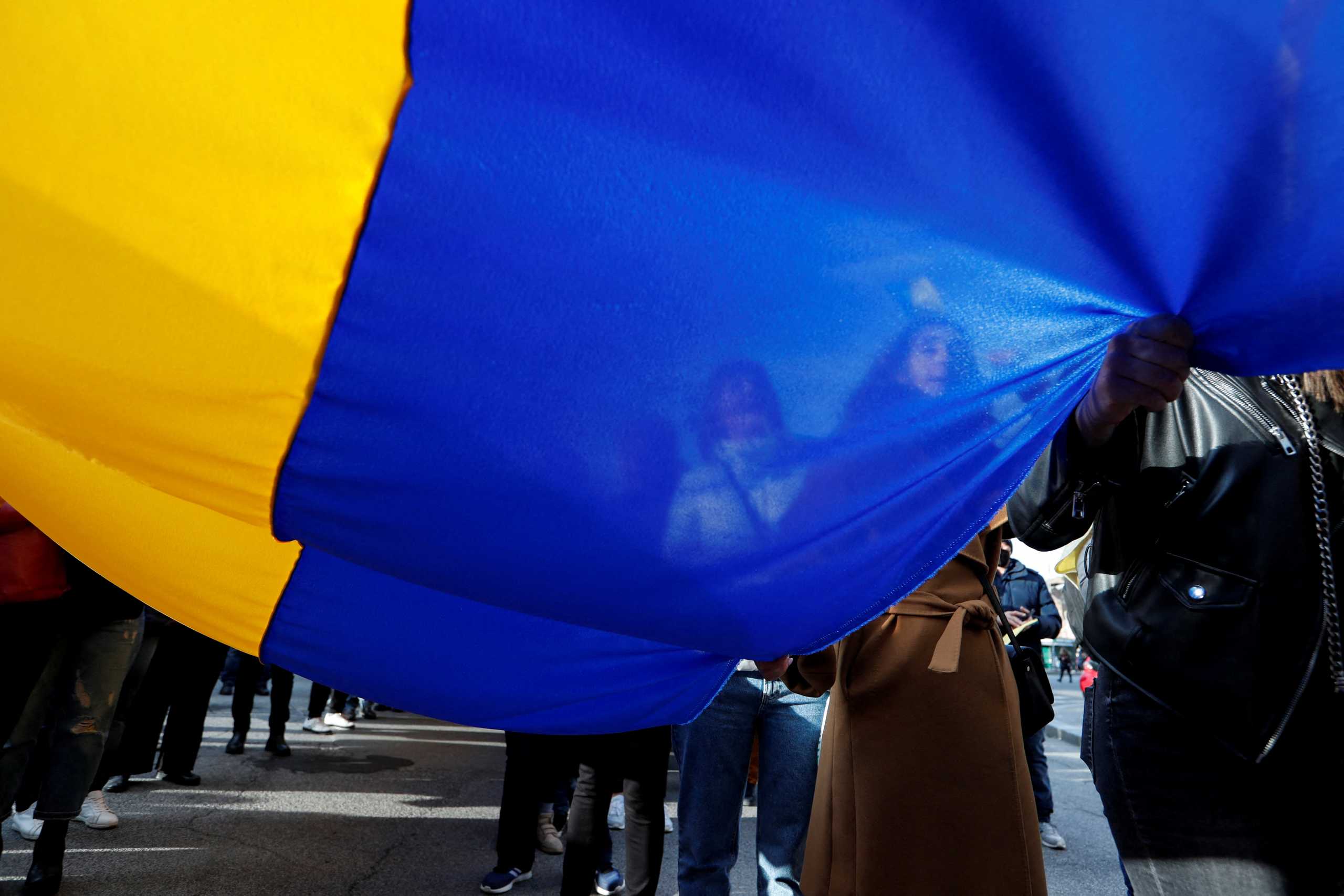 People hold up a Ukrainian flag during an anti-war protest at Piazza della Repubblica, after Russia launched a massive military operation against Ukraine, in Rome, Italy, February 27, 2022. REUTERS