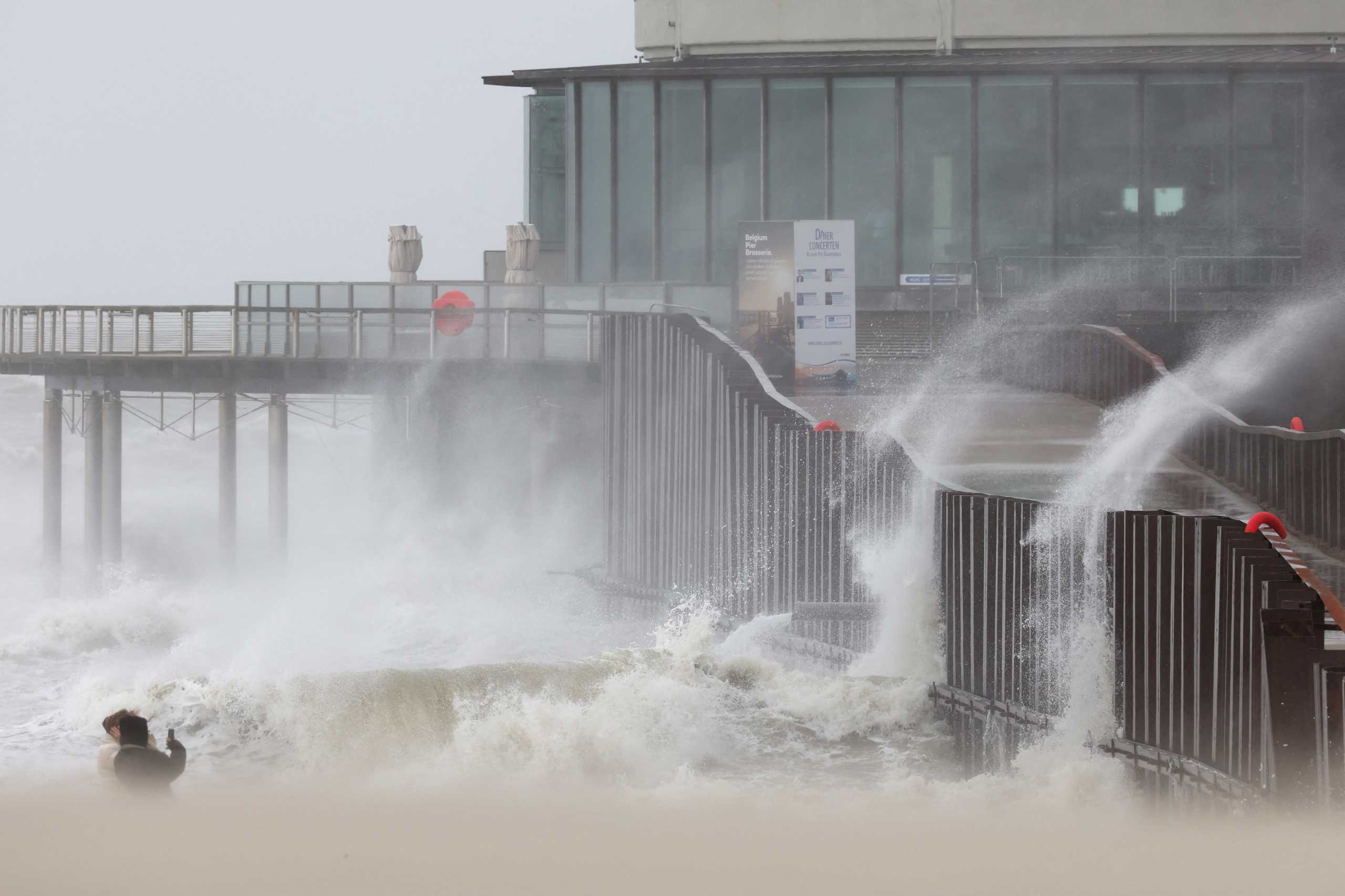 People take pictures as waves break on the beach in the wake of Storm Eunice in Ostend, Belgium, February 18, 2022. REUTERS