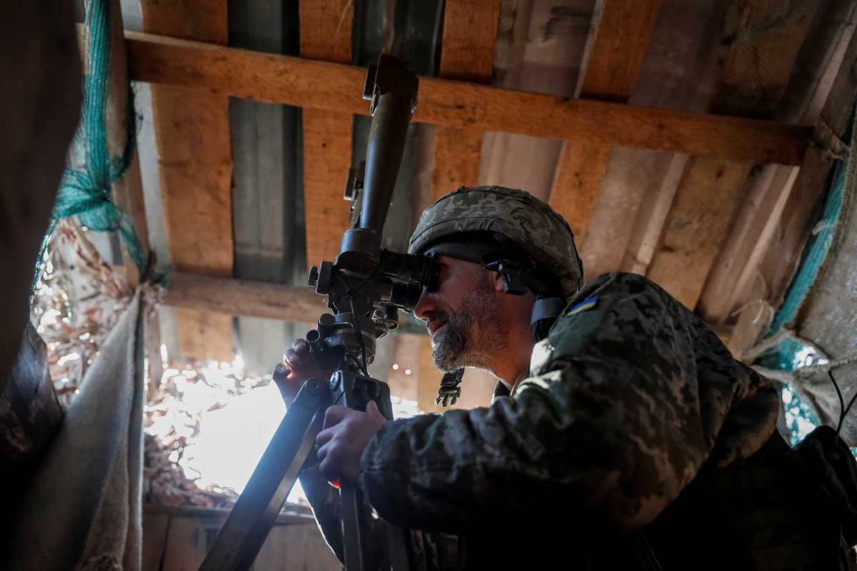 A Ukrainian service member uses a periscope while observing the area at a position on the front line near the village of Travneve in Donetsk region, Ukraine February 21, 2022. REUTERS
