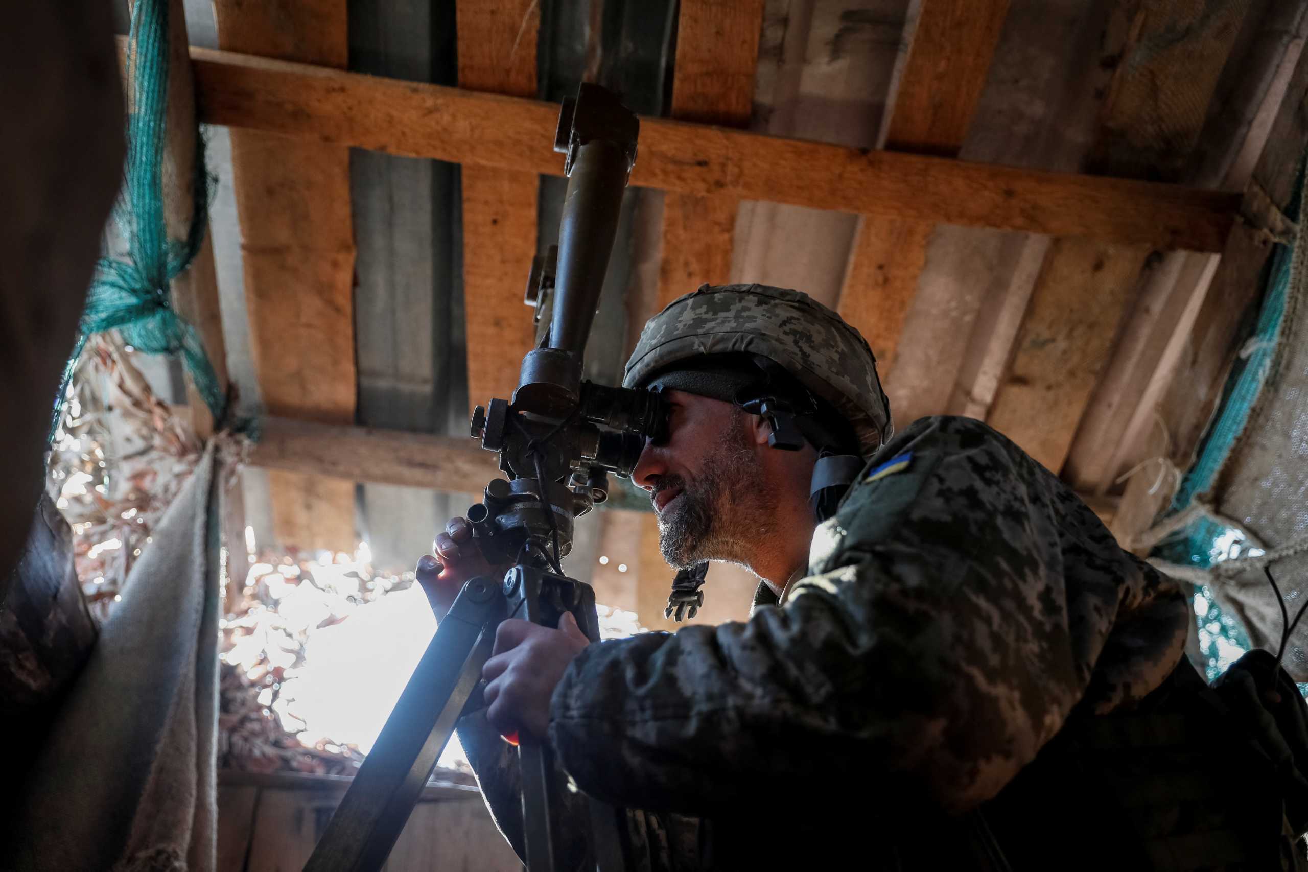 A Ukrainian service member uses a periscope while observing the area at a position on the front line near the village of Travneve in Donetsk region, Ukraine February 21, 2022. REUTERS