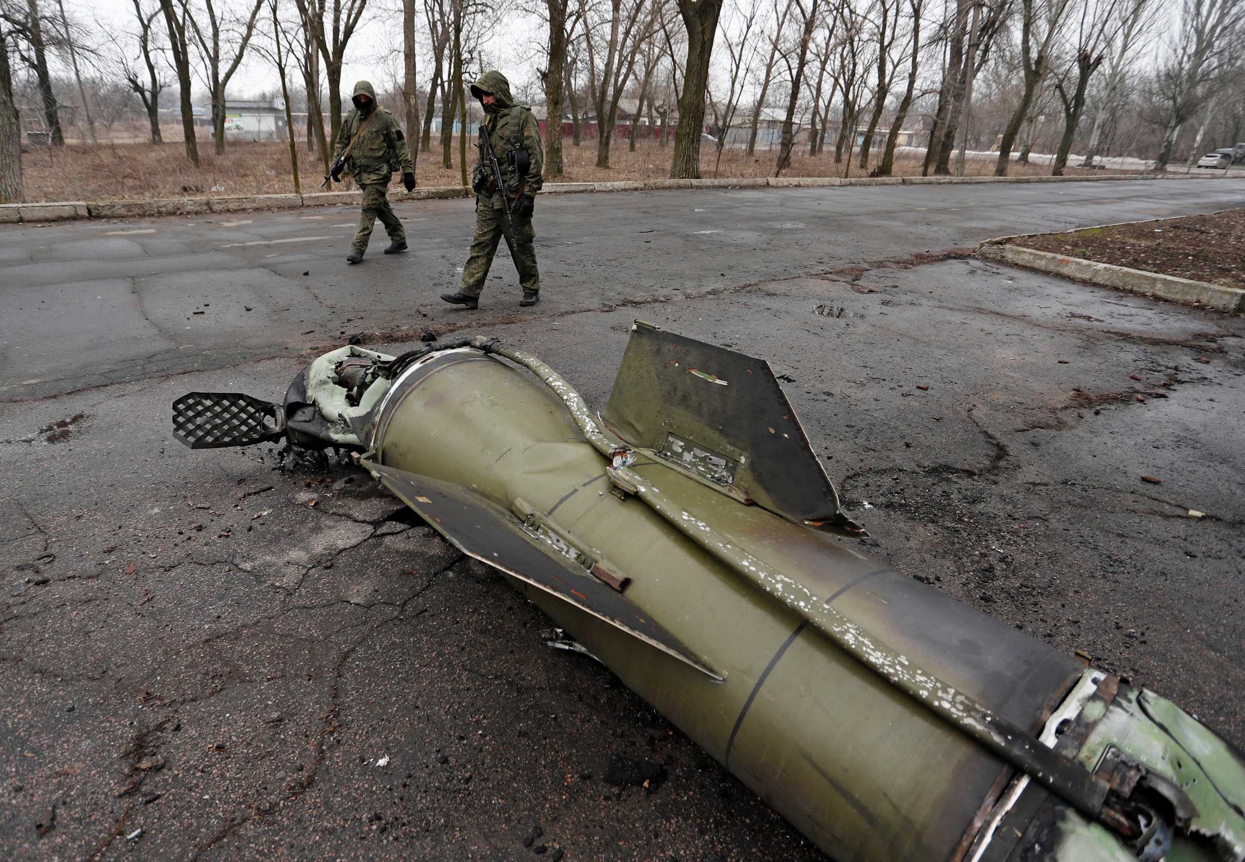 Militants of the self-proclaimed Donetsk People's Republic inspect the remains of a missile that landed on a street in the separatist-controlled city of Donetsk, Ukraine February 26, 2022. REUTERS