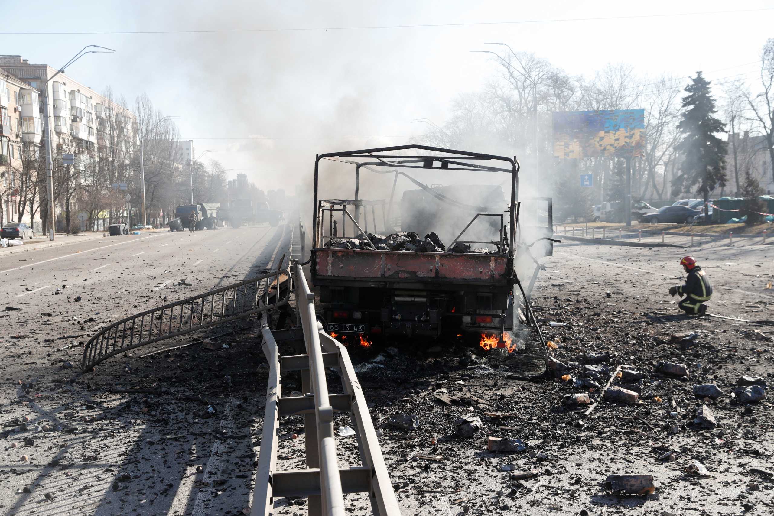 A Ukranian fireman kneels by a damaged vehicle, at the site of a fighting with Russian troops after Russia launched a massive military operation against Ukraine, in Kyiv, Ukraine February 26, 2022. REUTERS