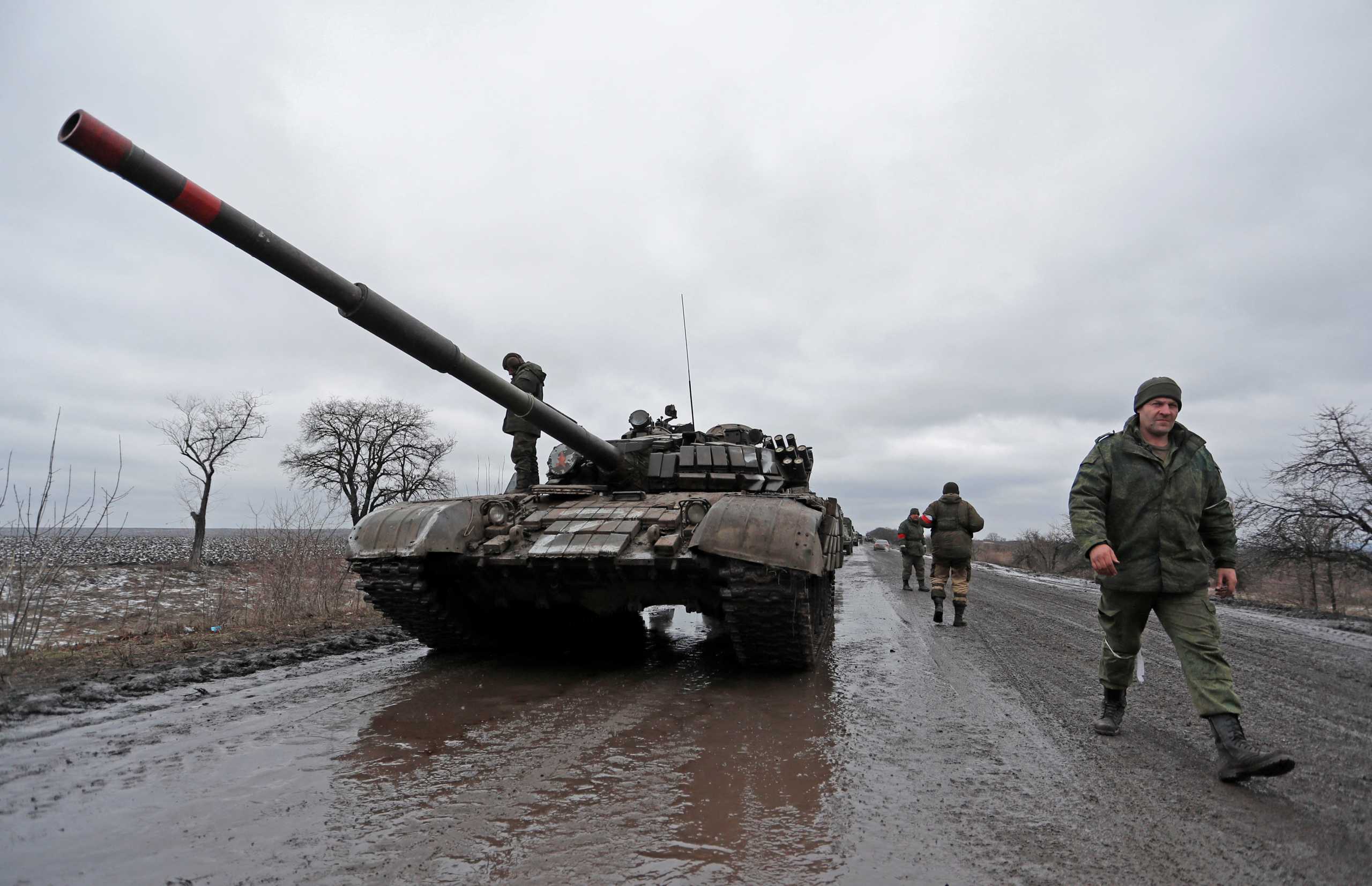 Servicemen of pro-Russian militia walk next to a military convoy of armed forces of the separatist self-proclaimed Luhansk People's Republic (LNR) on a road in the Luhansk region, Ukraine February 27, 2022. REUTERS