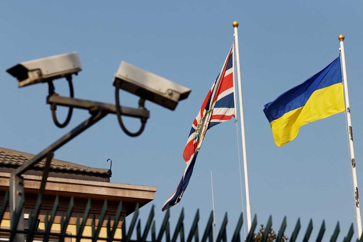 Surveillance cameras are seen near the flags of Ukraine and Union Jack fluttering at the British embassy in Beijing, China February 25, 2022. REUTERS