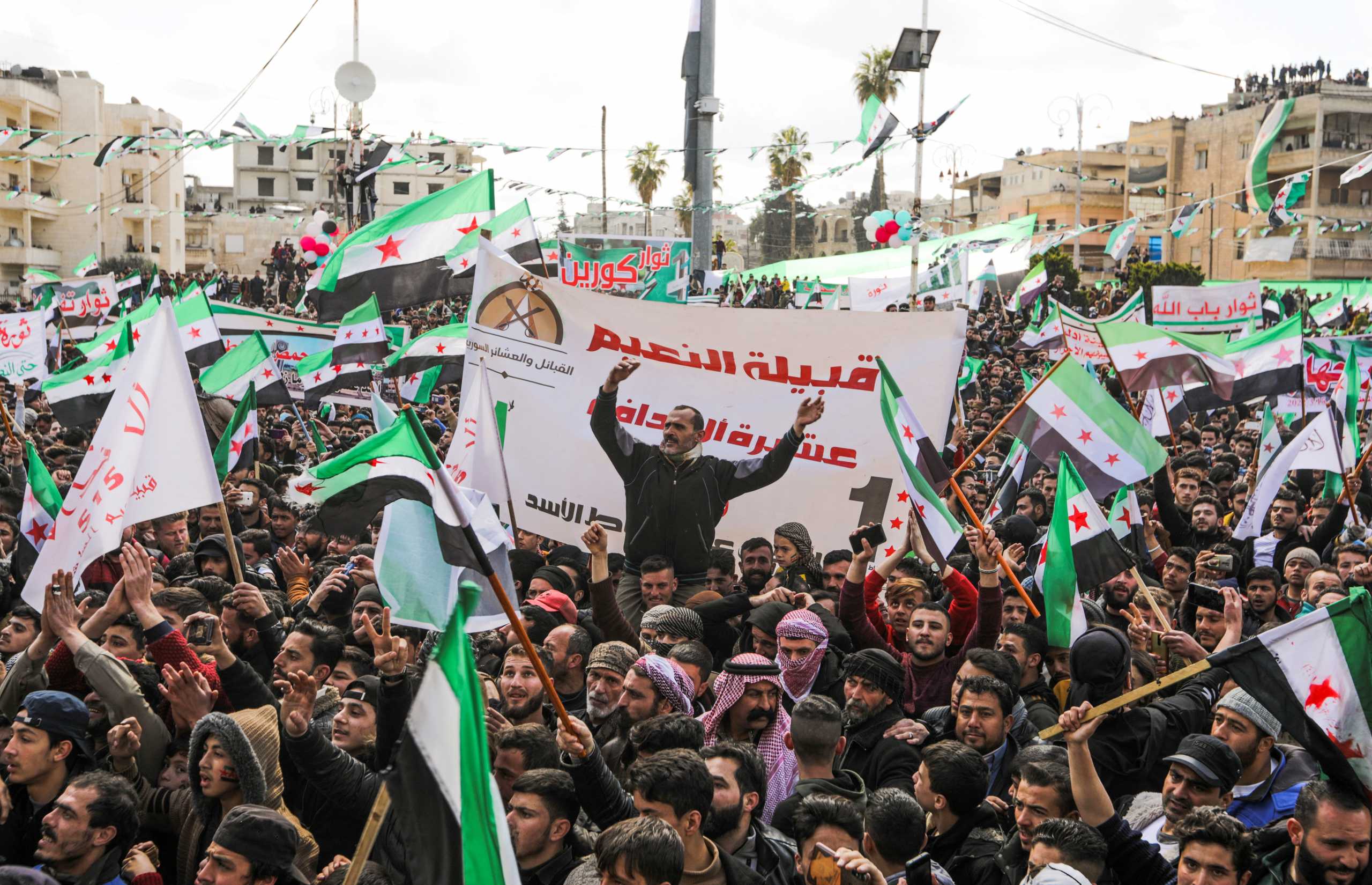 People carry banners and opposition flags during a demonstration, marking the 11th anniversary of the start of the Syrian conflict, in the opposition-held Idlib, Syria March 15, 2022. REUTERS
