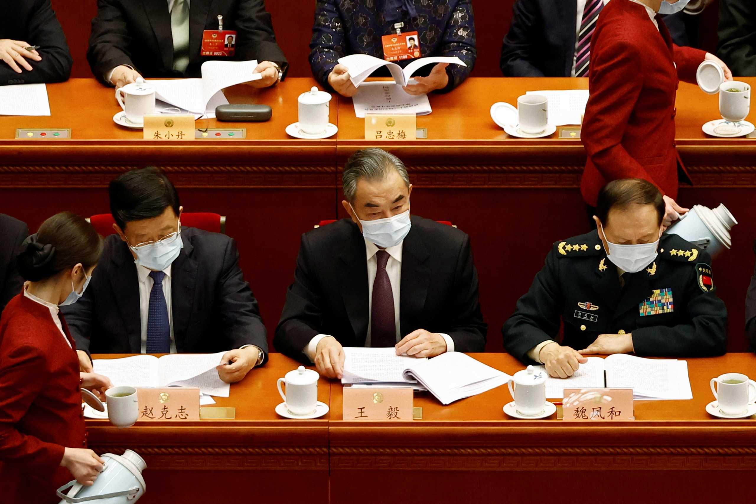 Attendants serve tea near Chinese State Councilor and Foreign Minister Wang Yi, State Councilor and Defense Minister Wei Fenghe, and State Councilor and Public Security Minister Zhao Kezhi at the opening session of the Chinese People's Political Consultative Conference (CPPCC) at the Great Hall of the People in Beijing, China March 4, 2022. REUTERS
