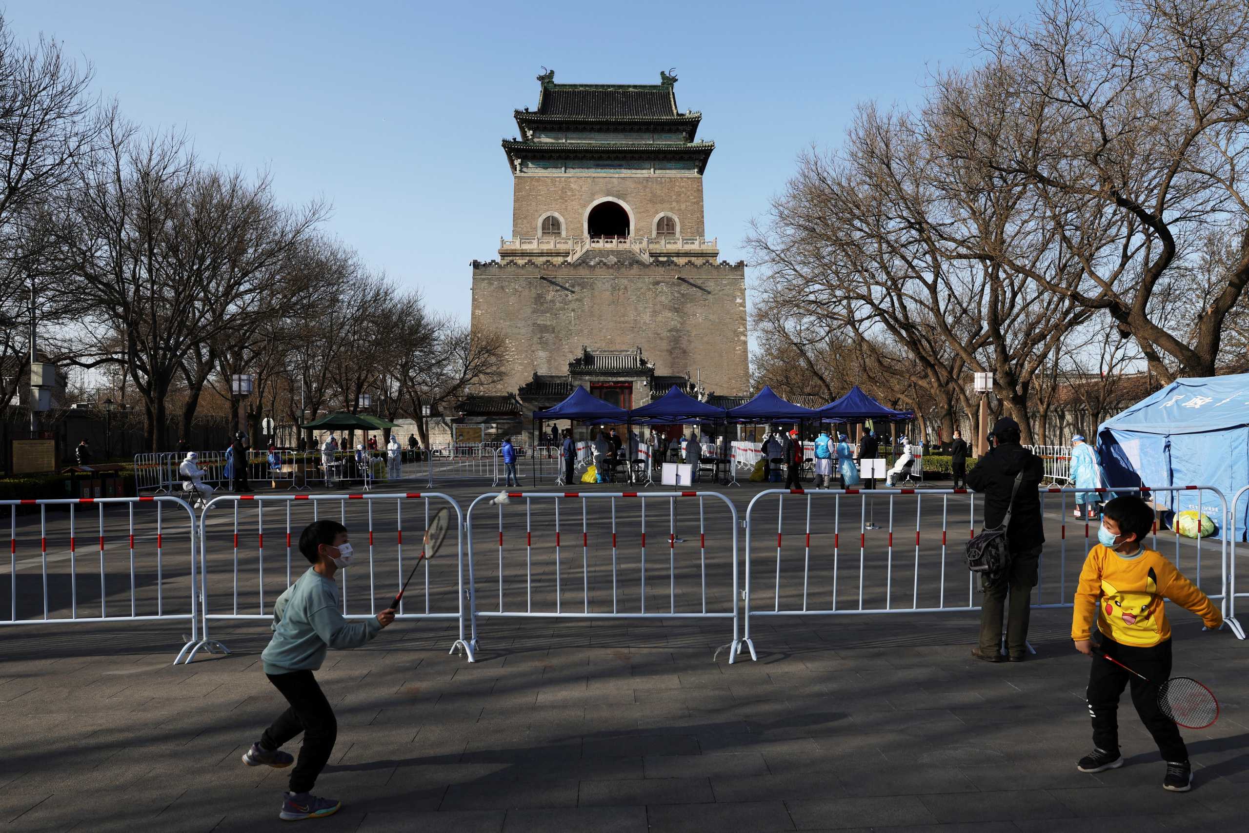 Children wearing face masks play badminton near a makeshift nucleic acid testing site at the Bell and Drum Tower Square, following the coronavirus disease (COVID-19) outbreak in Beijing, China March 21, 2022. REUTERS