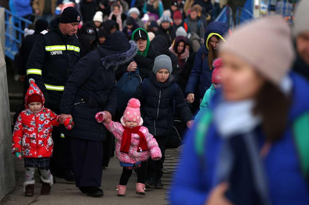 A woman walks with two kids, as they arrive by ferry after fleeing from Russia's invasion of Ukraine, at the Isaccea-Orlivka border crossing, Romania, March 8, 2022. REUTERS