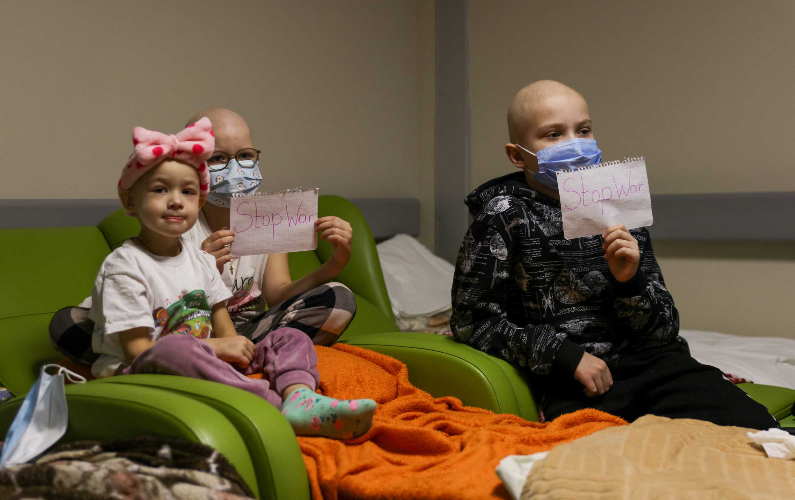 Children patients whose treatments are underway hold papers with the words "no war" written in them, at the hallways of the basement floor of Okhmadet Children's Hospital, as Russia's invasion of Ukraine continues, in Kyiv, Ukraine February 28, 2022. REUTERS