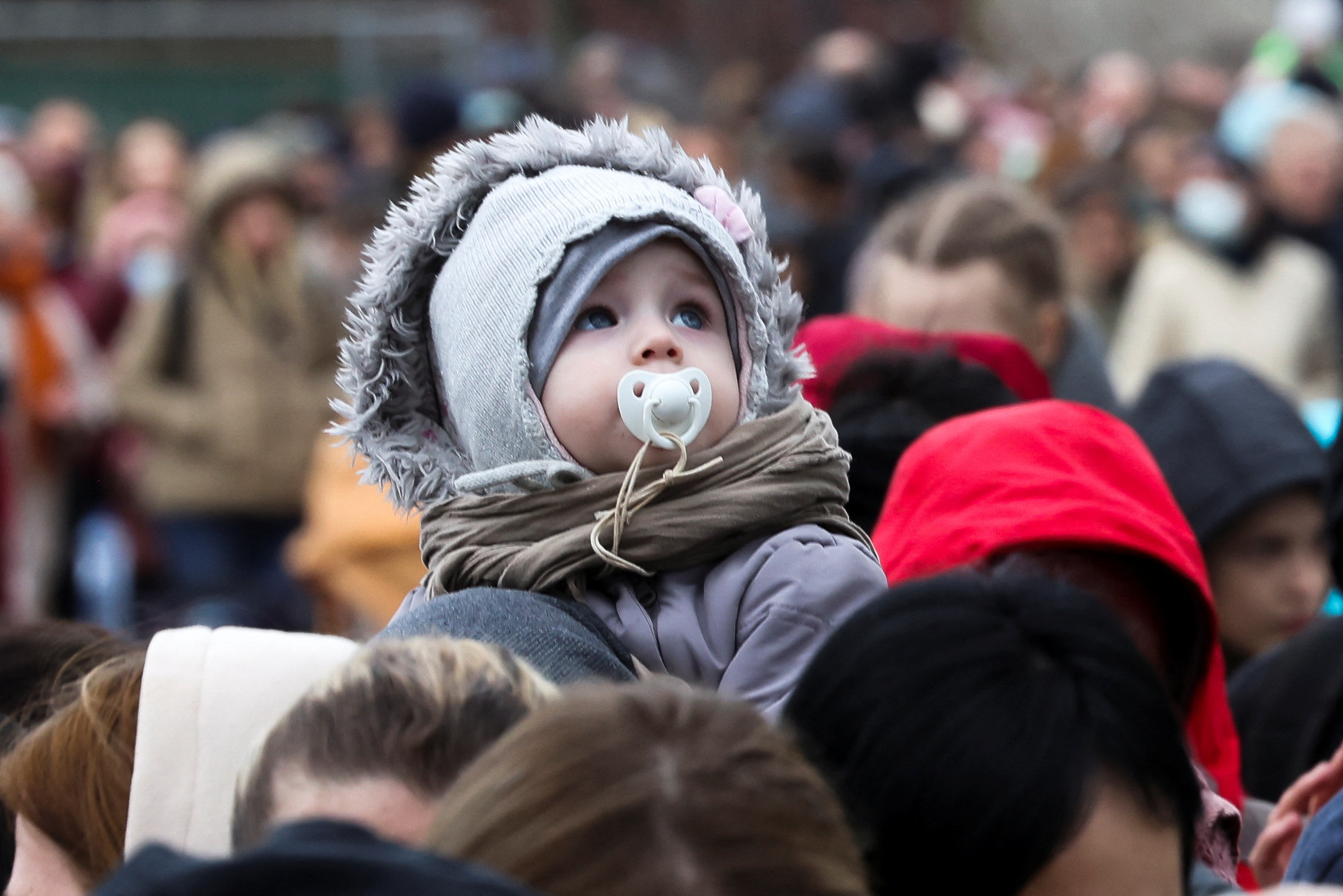 A child looks on as people wait outside an immigration office after fleeing from Ukraine to Belgium, following Russia's invasion of Ukraine, in Brussels, Belgium March 15, 2022. REUTERS