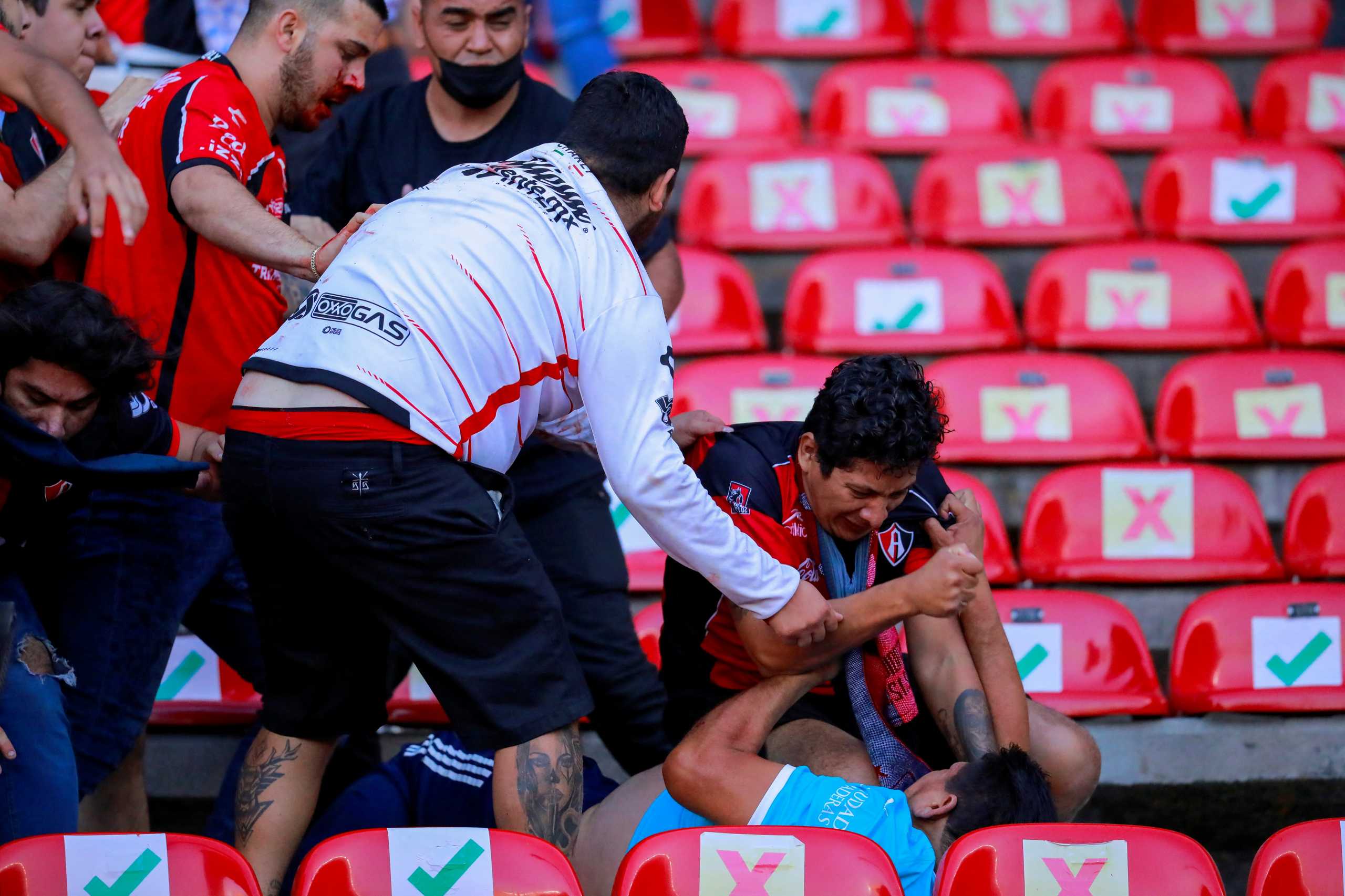 People are beaten at the seating area of the Corregidora stadium, leaving at least 22 injured in a brawl when soccer fans stormed the field during a top flight match between mid-table Queretaro and last year's Liga MX champions Atlas, in Queretaro, Mexico  March 5, 2022. Picture taken on March 5, 2022. REUTERS