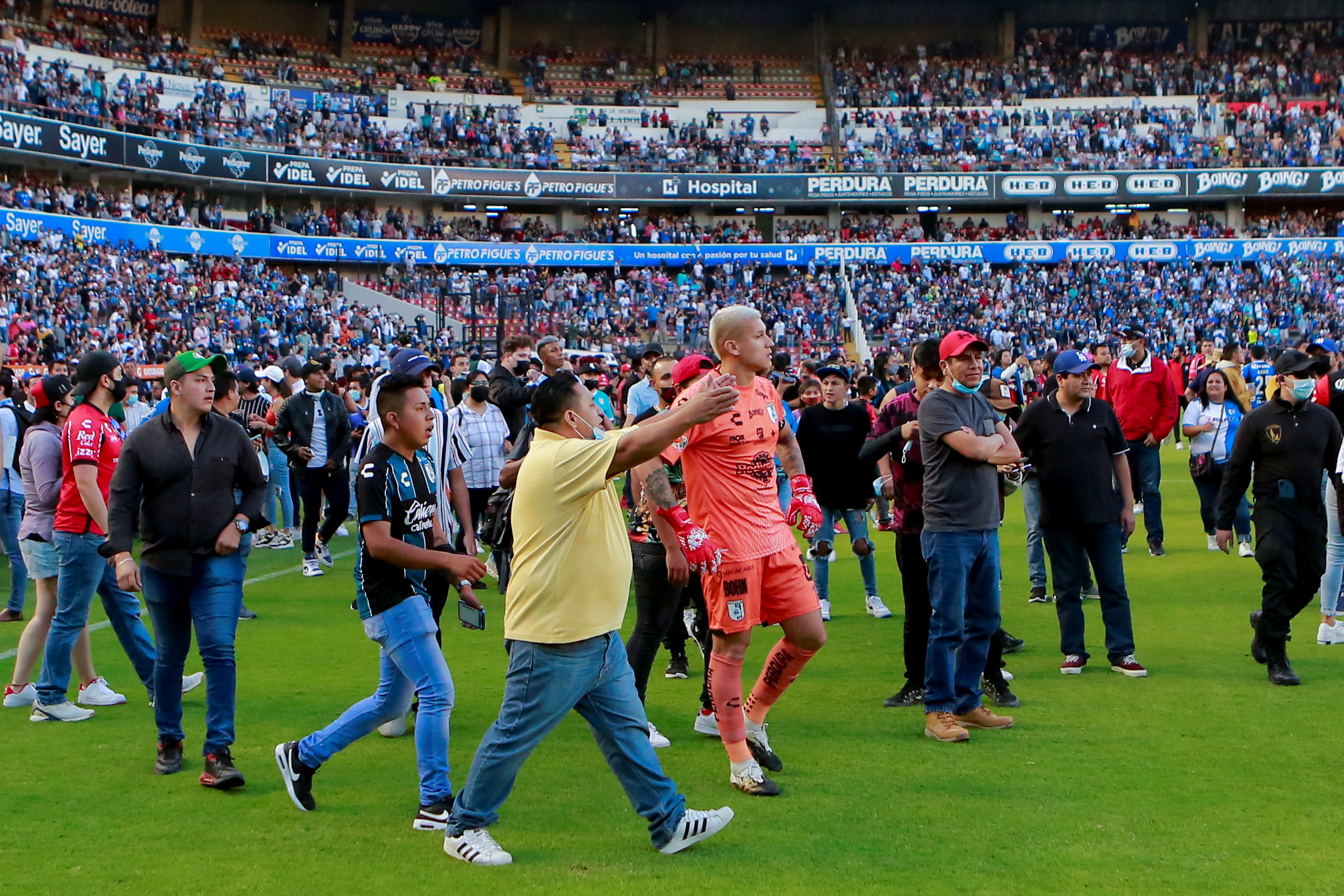 Soccer players and people walk on the field at the Corregidora stadium after clashes leave least 22 people injured in a brawl when soccer fans stormed the field during a top flight match between mid-table Queretaro and last year's Liga MX champions Atlas, in Queretaro, Mexico March 5, 2022. Picture taken on March 5, 2022. REUTERS