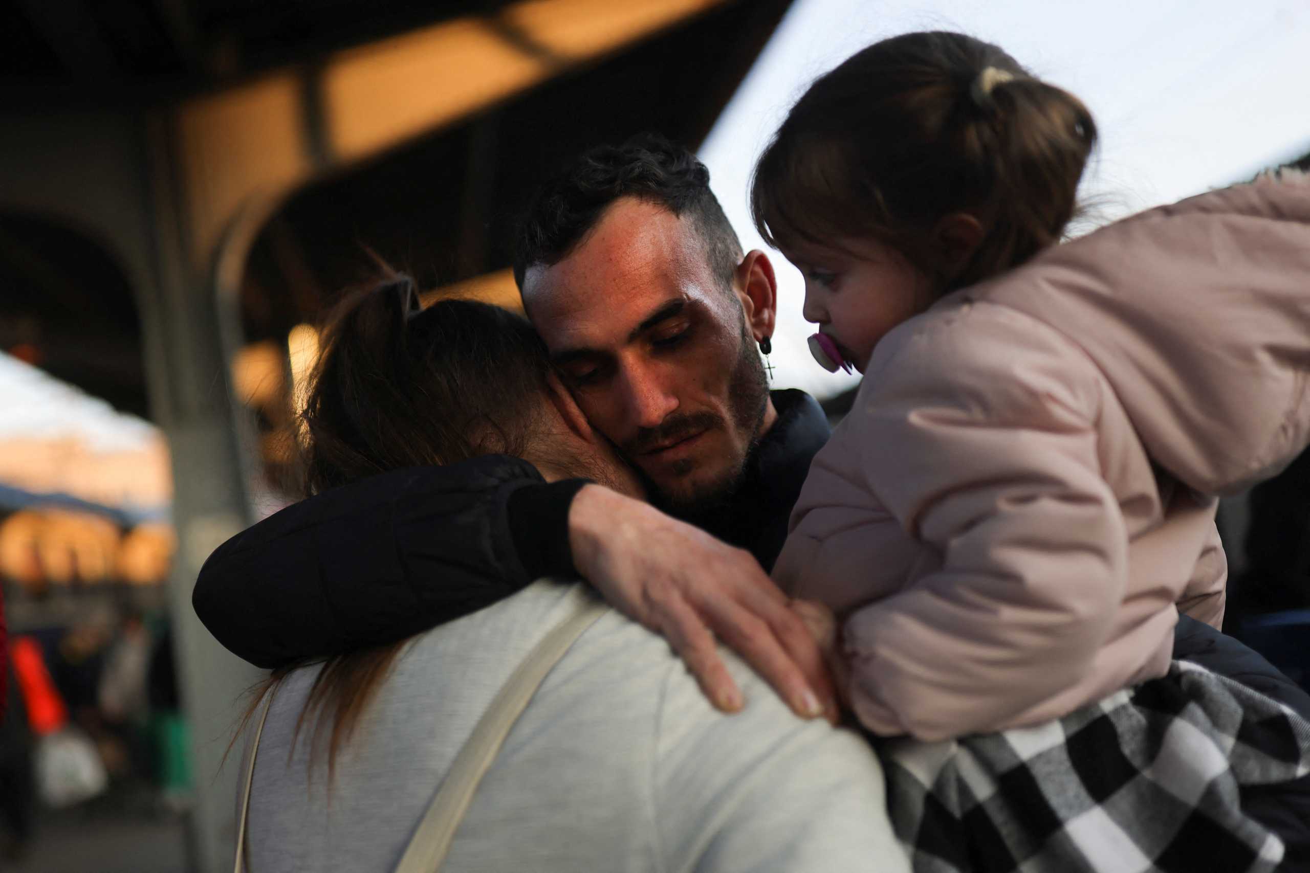 A Ukrainian refugee says goodbye to his wife and daughter before they board a train for Budapest and after arriving from the border with Ukraine fleeing their country following the Russian invasion, at North Railway Station in Bucharest, Romania, March 14, 2022. REUTERS