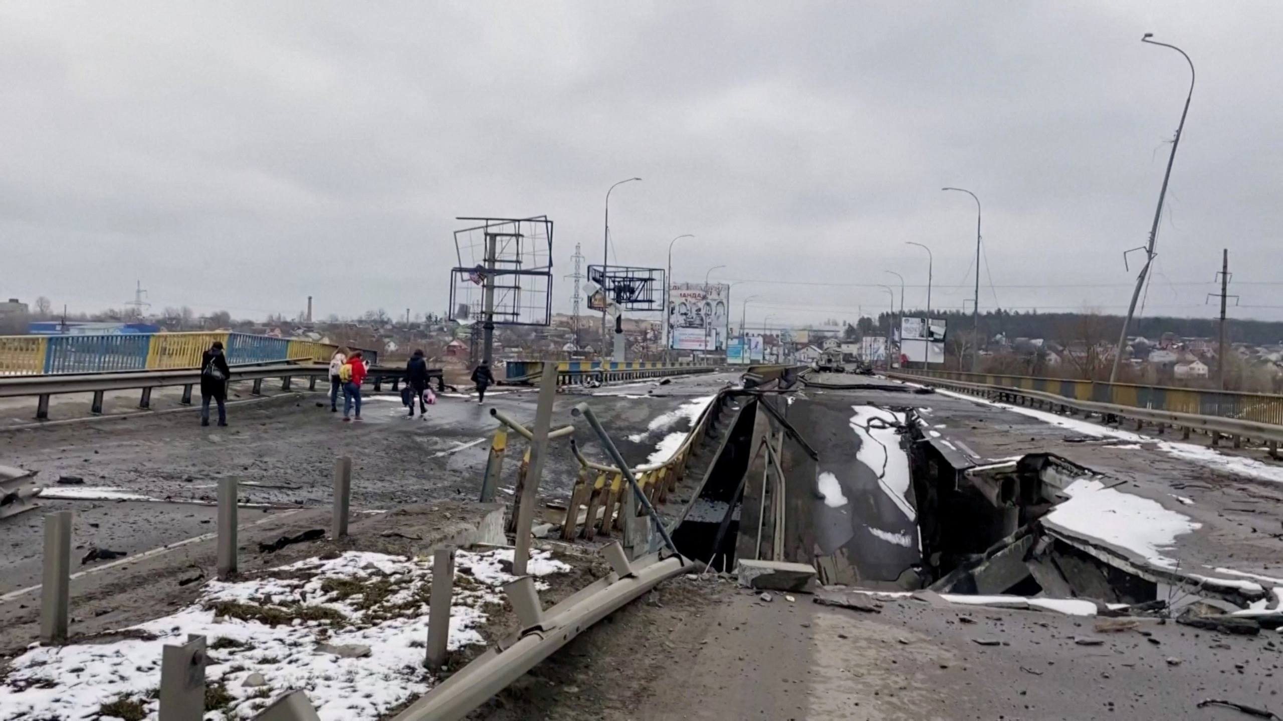 People walk on a partially destroyed bridge, amid Russia's ongoing invasion of Ukraine, in Bucha, Ukraine, March 2, 2022 in this still image taken from video. Video taken March 2, 2022.  REUTERS
