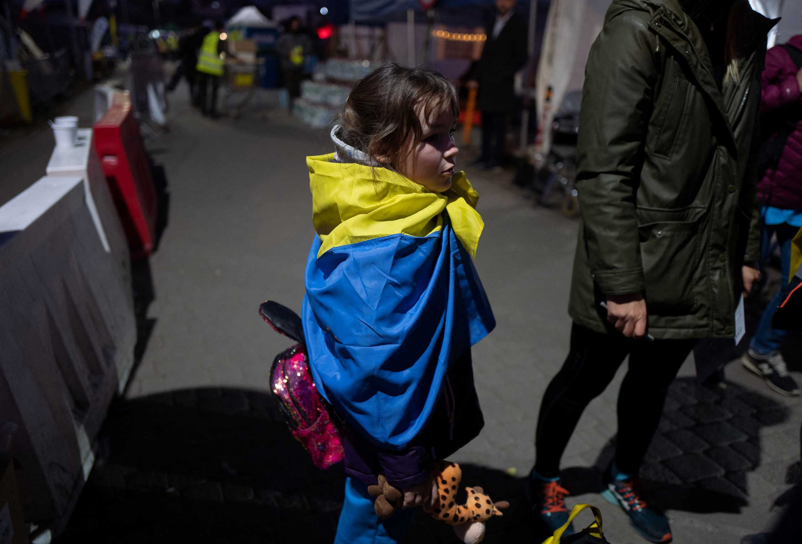 Anastasia, 8, wraps herself in a Ukrainian flag, amid Russia's invasion of Ukraine, at the border crossing in Medyka, Poland March 23, 2022. REUTERS