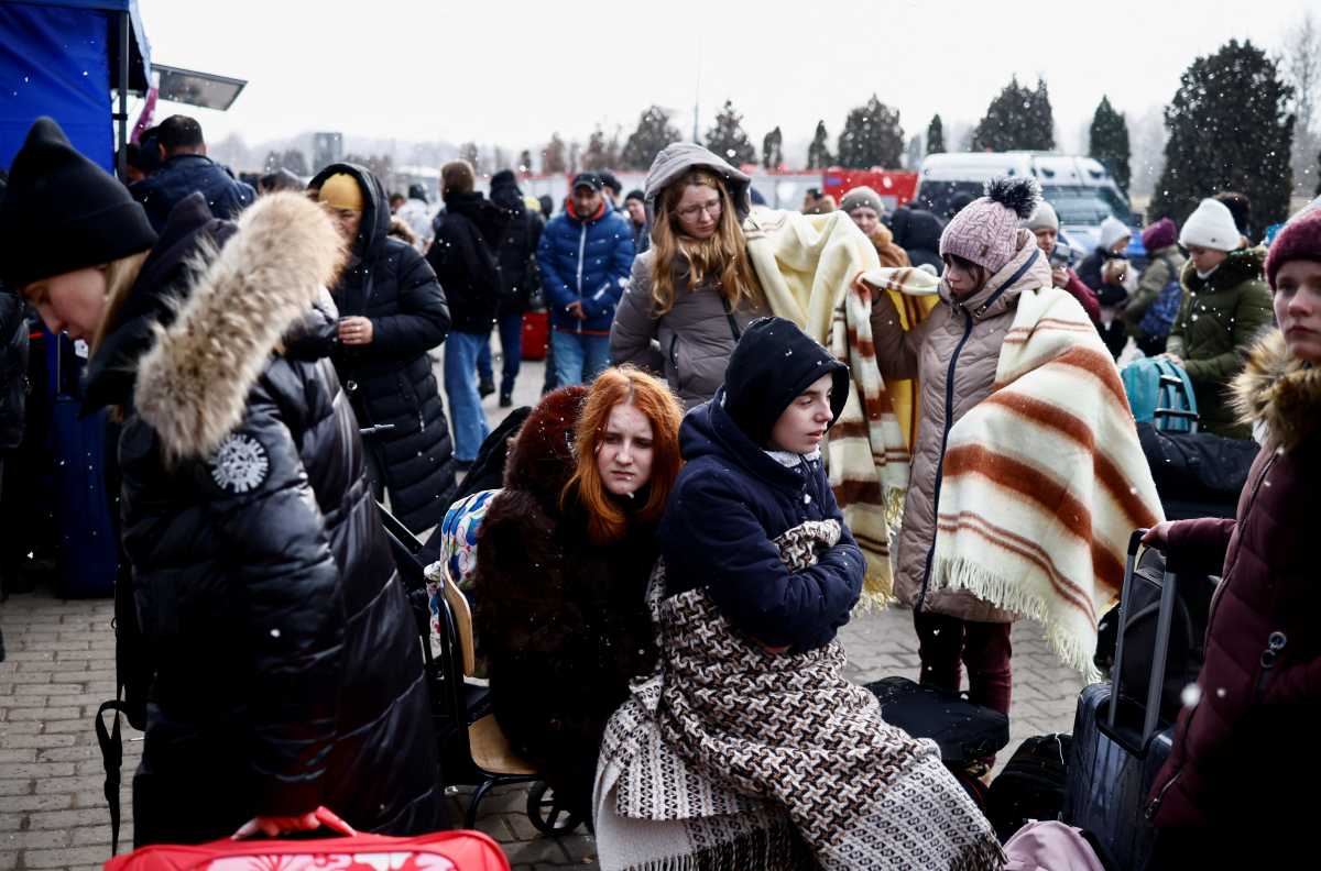 People wait outside a temporary accommodation centre after fleeing Russian invasion of Ukraine, in Korczowa, Poland, March 3, 2022. REUTERS