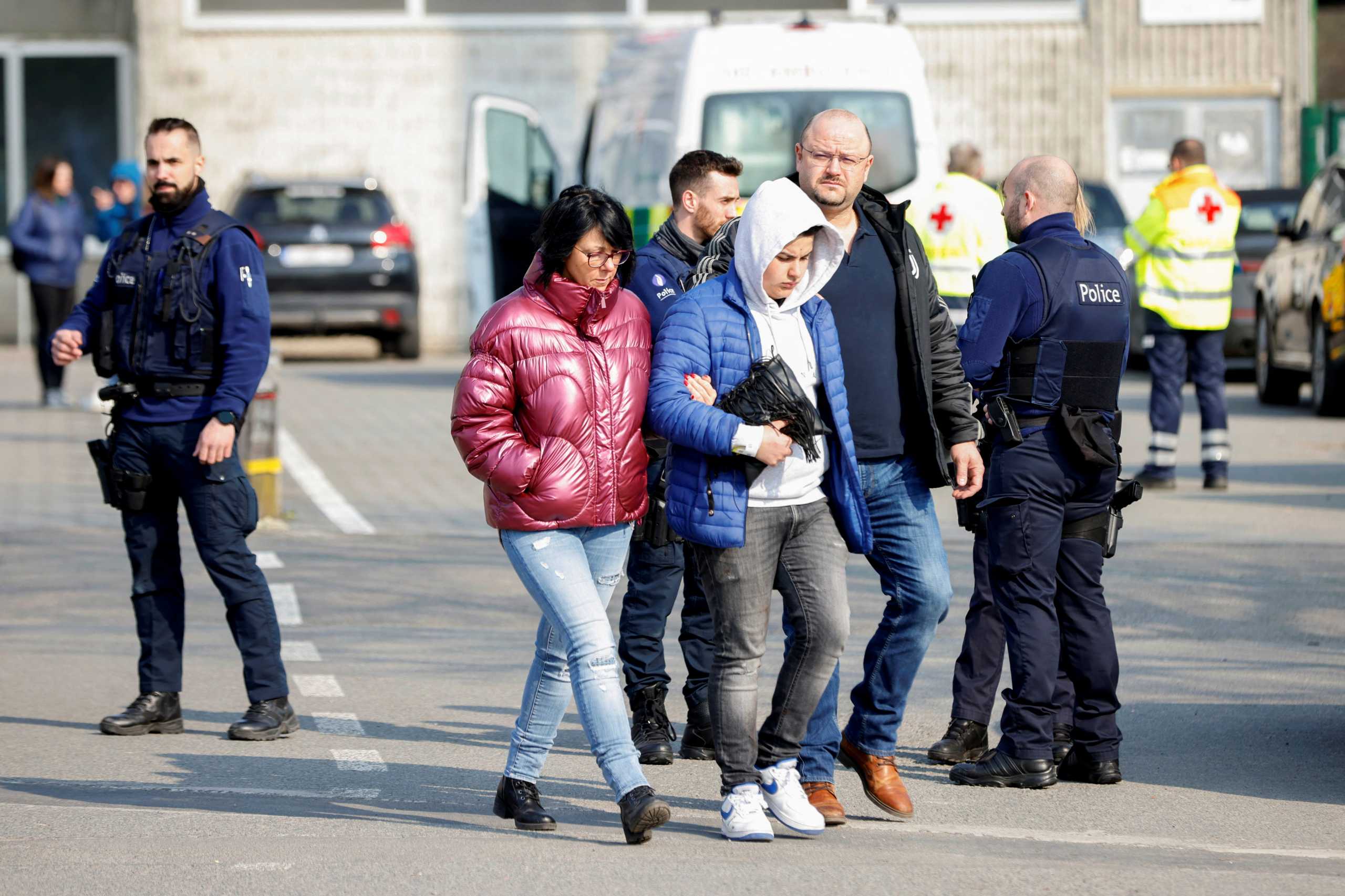 People walk as police officers keep guard near the site where a vehicle drove into a group of Belgian carnival performers who were preparing for a parade in the village of Strepy-Bracquegnies, Belgium March 20, 2022. REUTERS