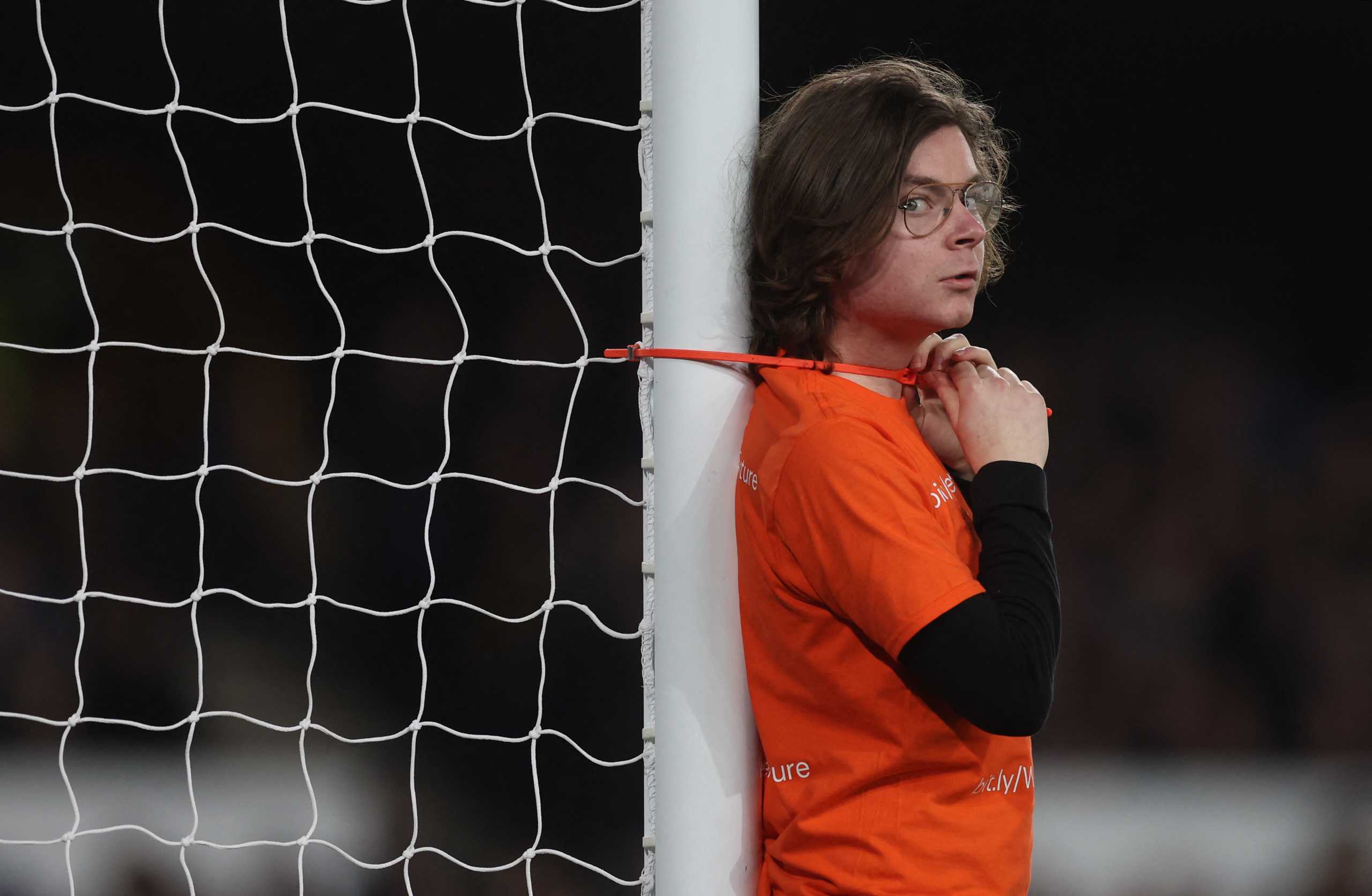 Soccer Football - Premier League - Everton v Newcastle United - Goodison Park, Liverpool, Britain - March 17, 2022 A protester ties himself to a goalpost during the match Action Images via Reuters