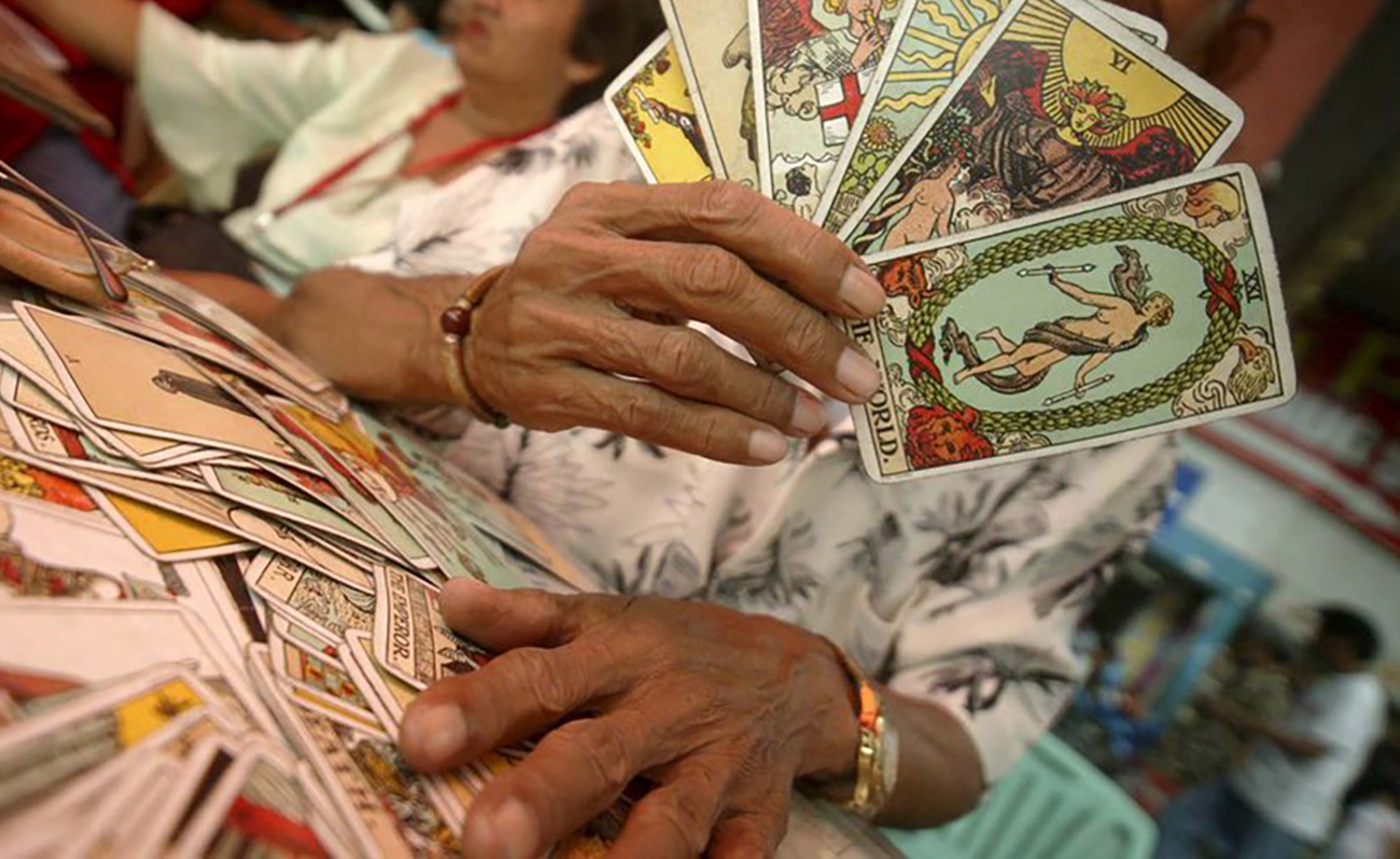 epa00857938 A Filipino claiming to be a fortune teller holds up tarot cards outside the Quiapo Church in Manila, Philippines on Wednesday 08 November 2006. Fortune tellers thrive in the Philippines as many Filipinos can be superstitious and are led to believe in individuals who claim to be able to predict one's future or fate, often in exchange for a reasonable fee.  EPA