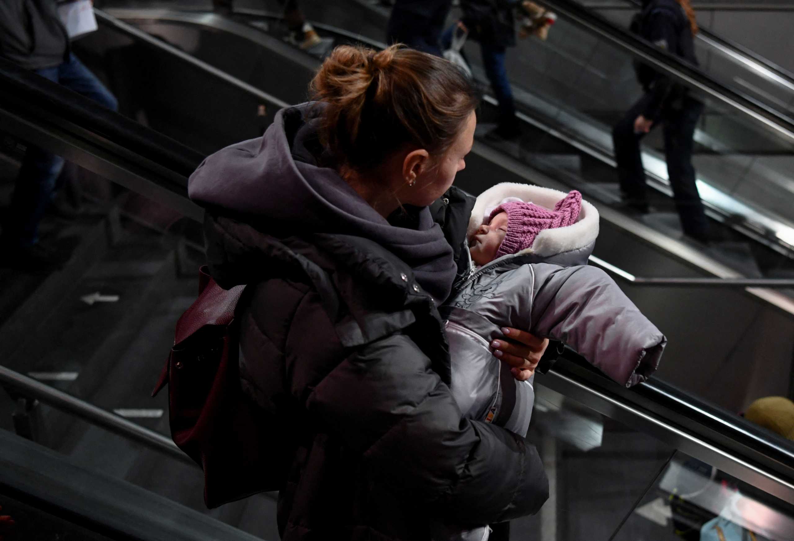 A woman carries a child after arriving at Berlin's central station on a train from Poland, amid Russia's invasion of Ukraine, in Berlin, Germany, March 6, 2022. REUTERS