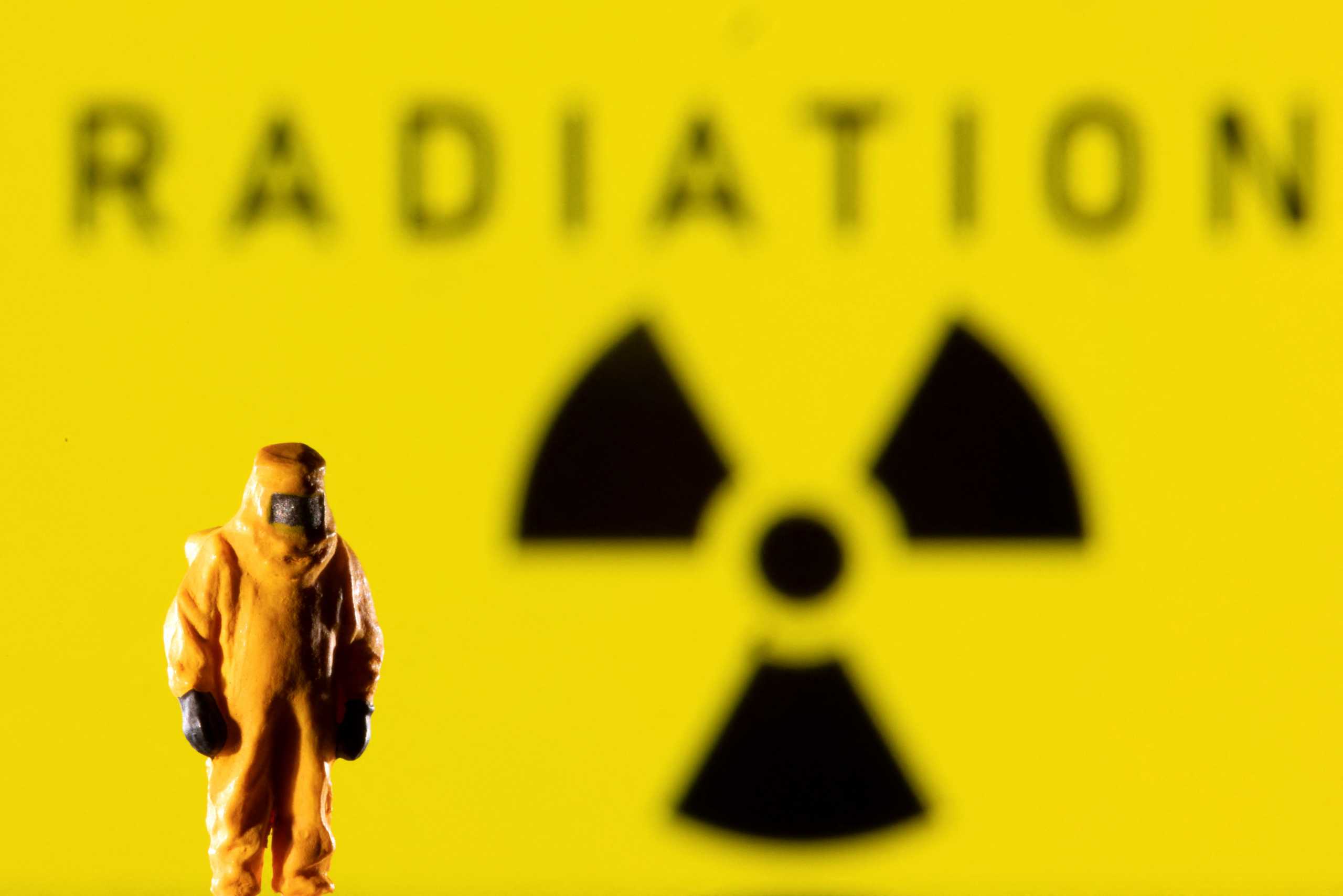 A figurine in protective equipment is seen in front of a displayed Radiation sign in this illustration taken March 9, 2022. REUTERS