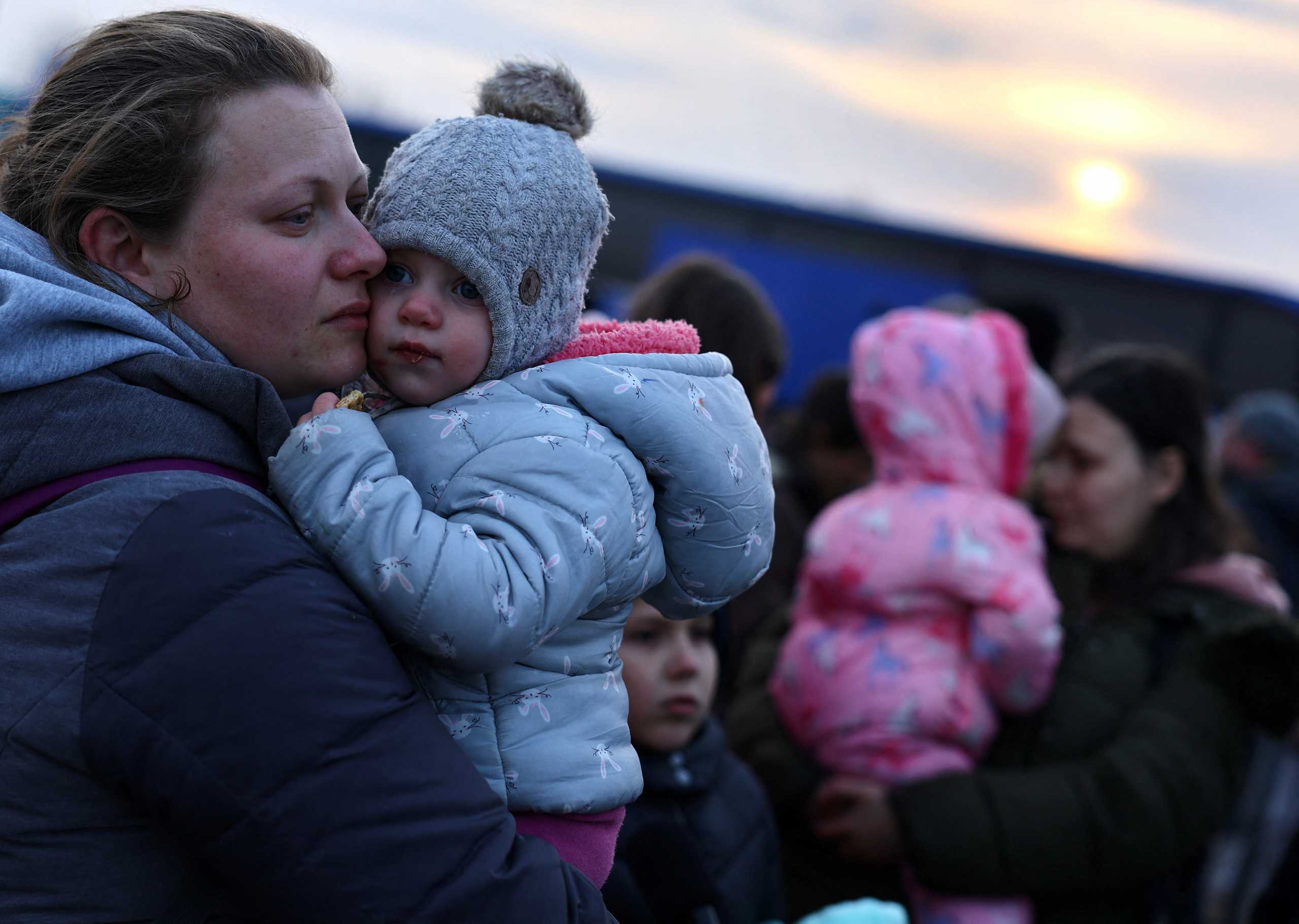 Ukrainian women who were fleeing Russian invasion of Ukraine hold their children as they arrive at a temporary camp in Przemysl, Poland, March 1, 2022.   REUTERS
