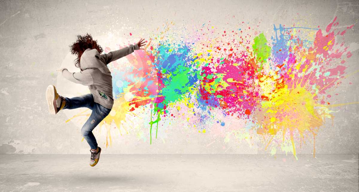 Happy teenager jumping with colorful ink splatter on urban background concept