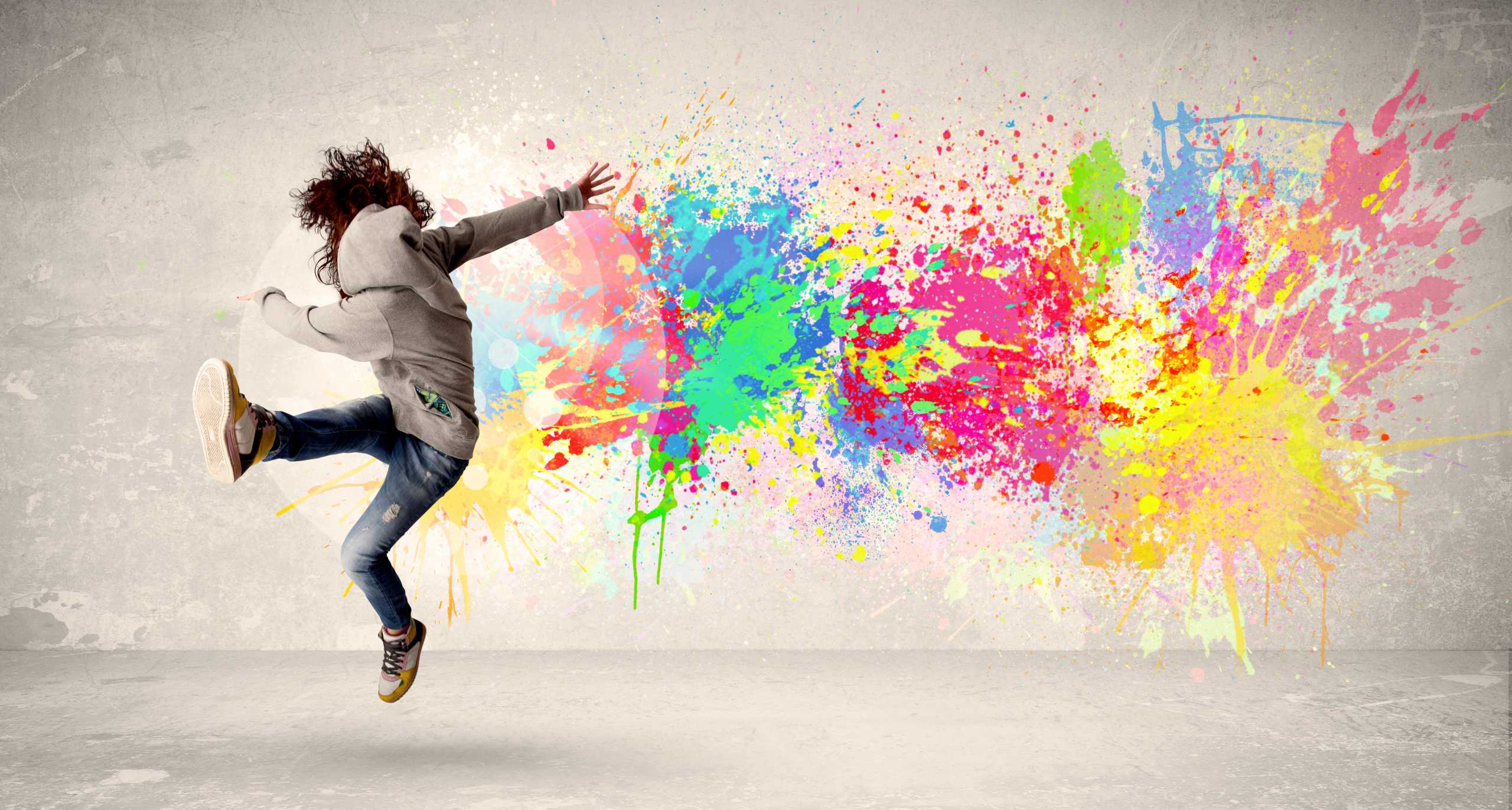 Happy teenager jumping with colorful ink splatter on urban background concept
