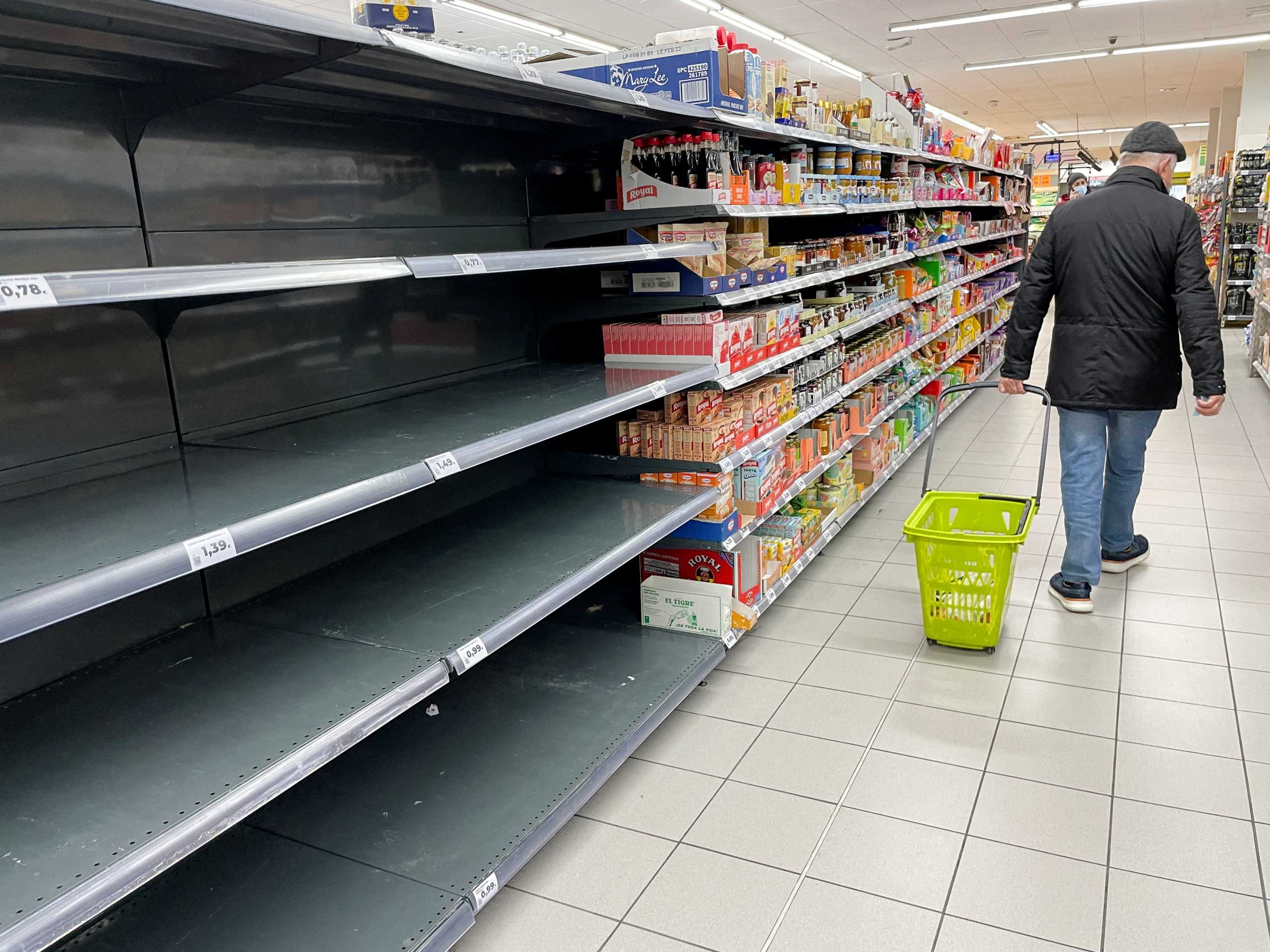 FILE PHOTO: A man walks past empty shelves during a truck drivers' strike against rising fuel prices, that is causing episodic shortages of some fresh products in supermarkets across the country, in Madrid, Spain, March 23, 2022. REUTERS