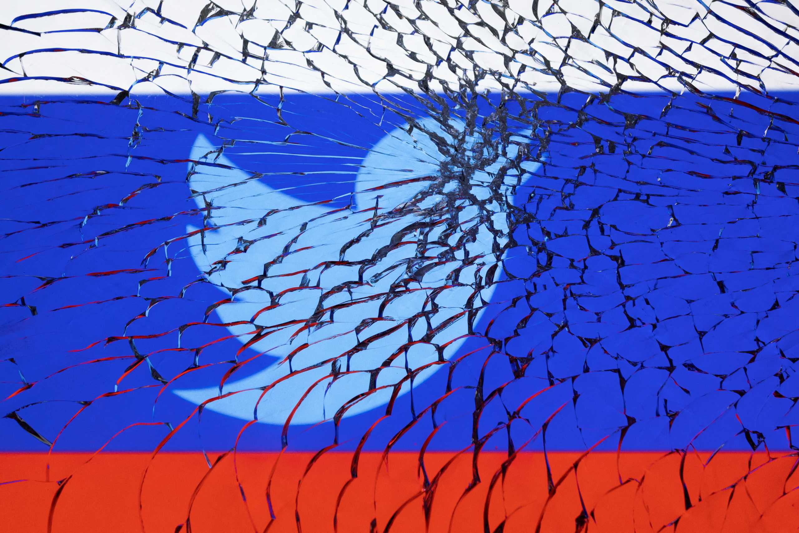 Twitter logo and Russian flag are seen through broken glass in this illustration taken March 1, 2022. REUTERS