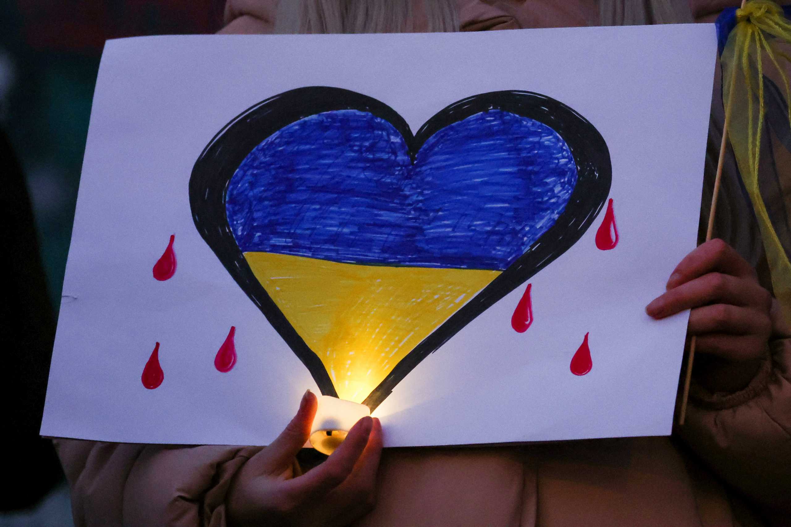 A person holds a candle and a poster during a vigil held in support of Ukraine, following Russia's invasion of Ukraine, in Liverpool, Britain, March 1, 2022. REUTERS