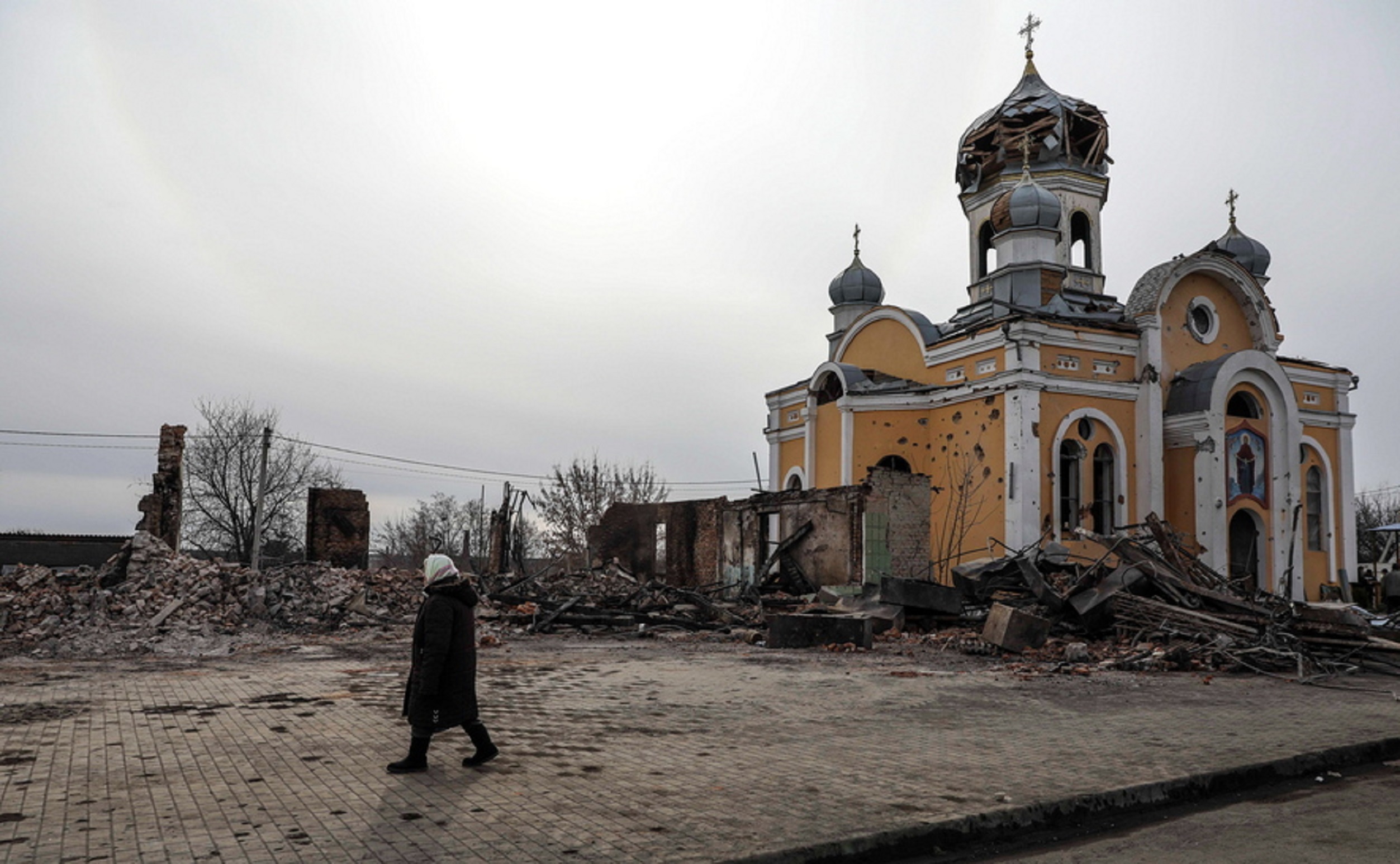 epa09819961 A woman passes near the Rus Orthodox Foreign Church partially destroyed after being bombed by Russian aircraft, in Malyn, Ukraine, 12 March 2022. Russian troops entered Ukraine on 24 February prompting the country's president to declare martial law and triggering a series of announcements by Western countries to impose severe economic sanctions on Russia.  EPA