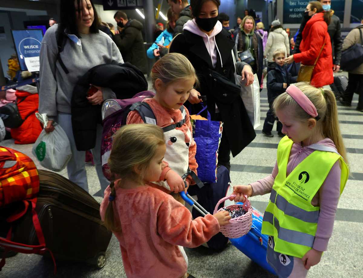 Nikola Ryba, 4, a Polish girl volunteering with her mother, distributes candies at the main railway station, to people fleeing the Russian invasion of Ukraine in Krakow, Poland, March 15, 2022.   REUTERS