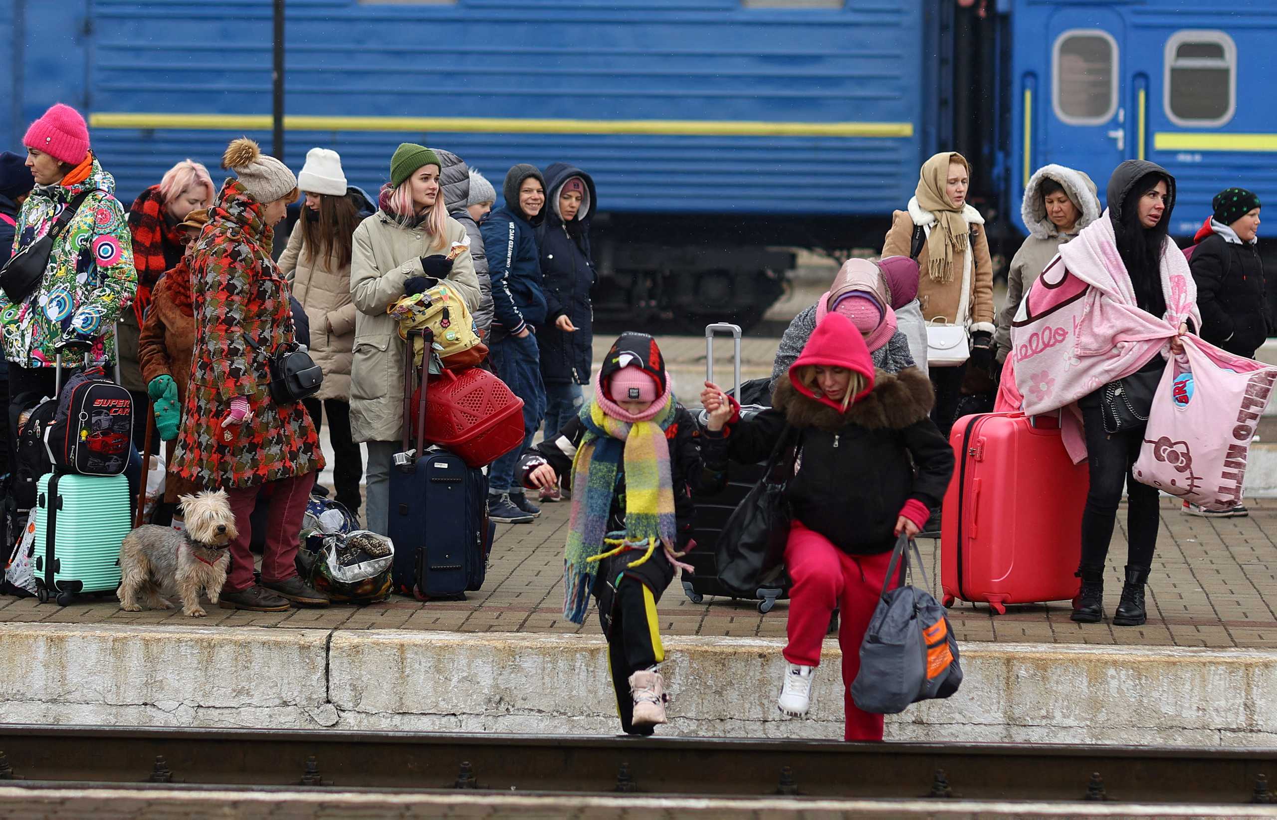 FILE PHOTO: Refugees crossing the rail tracks as they try to reach trains to Poland following Russia’s invasion of Ukraine at the main train station in Lviv, Ukraine, March 4, 2022.   REUTERS
