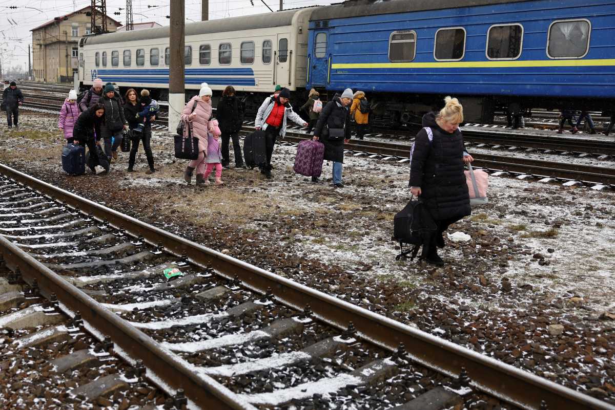 People walk with their luggage amid train tracks, as refugees flee Russia's invasion of Ukraine, in the train station in Lviv, Ukraine March 5, 2022. REUTERS
