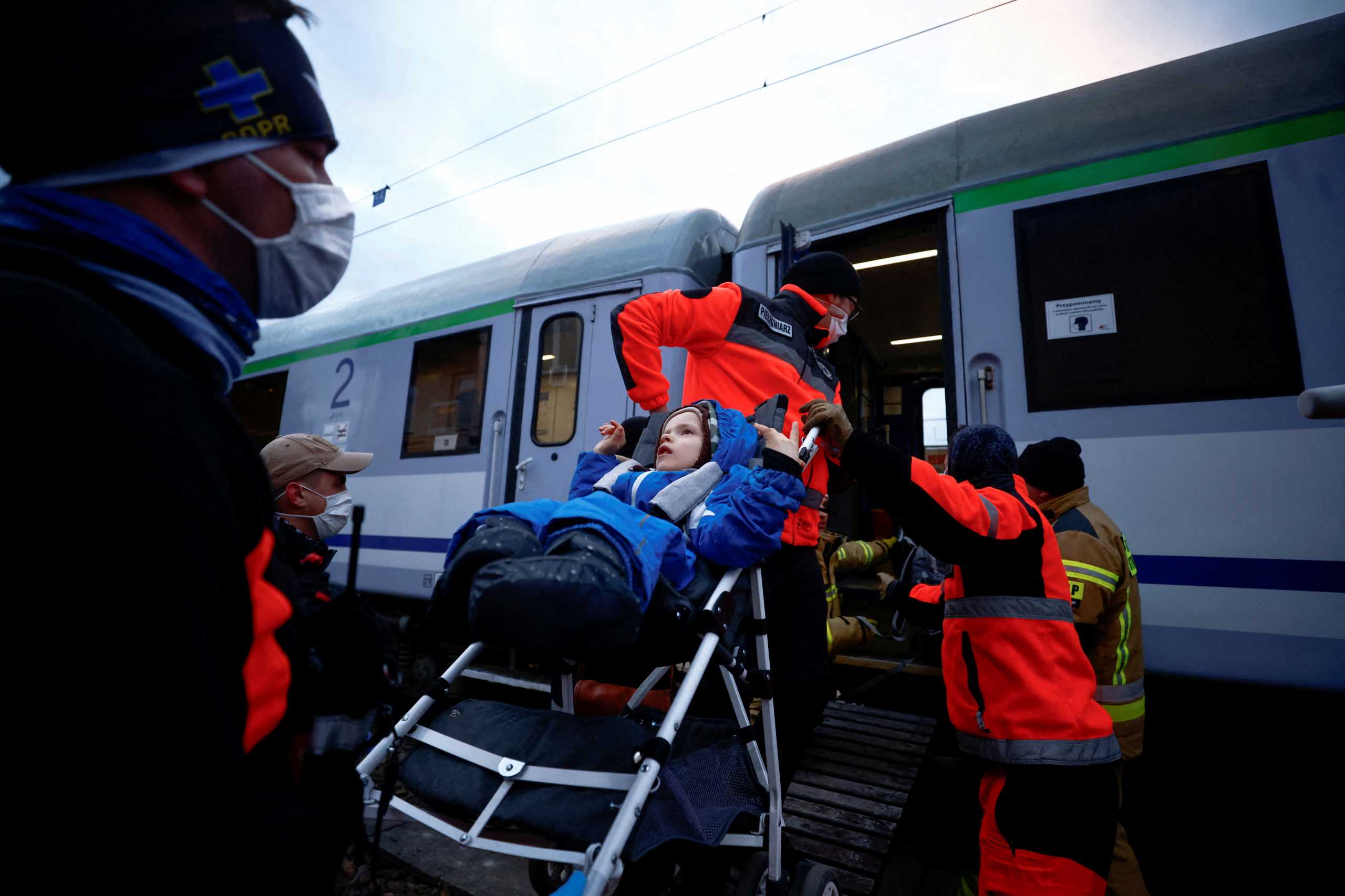 Paramedics help a sick child to board a train transformed for medical transport, as 20 children with chronic illnesses and cancer diagnosis came from Kharkiv fleeing the Russian invasion of Ukraine, at the border checkpoint in Medyka, Poland, March 10, 2022. REUTERS