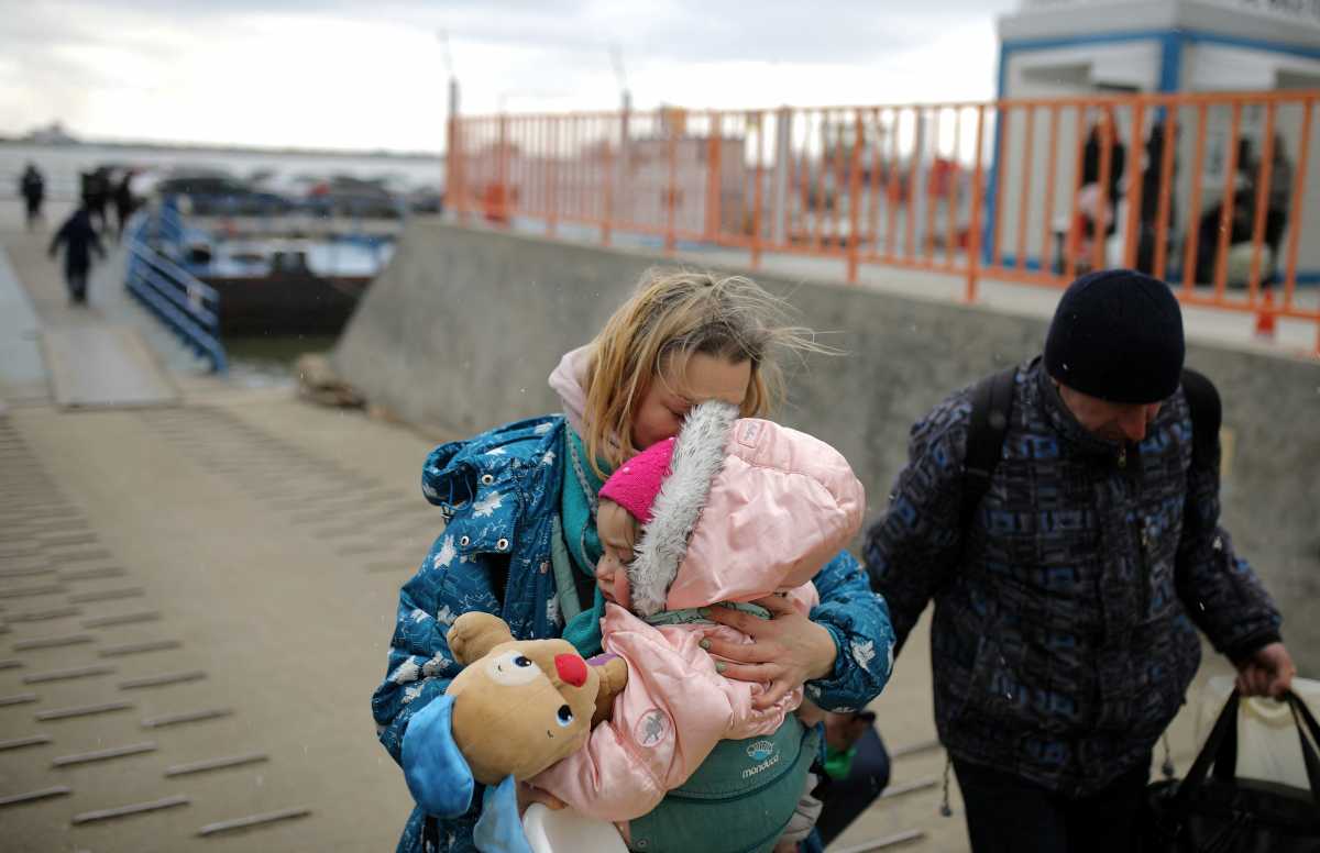 A woman carries a child, as they arrive by ferry after fleeing from Russia's invasion of Ukraine, at the Isaccea-Orlivka border crossing, Romania, March 9, 2022. REUTERS