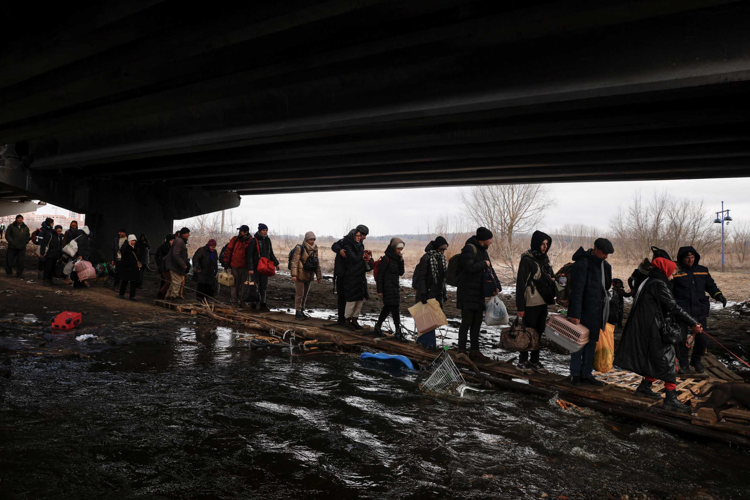 People fleeing advancing Russian forces file across wooden planks crossing Irpin River below a destroyed bridge as Russia's attack on Ukraine continues in Irpin outside Kyiv, Ukraine, March 9, 2022. REUTERS