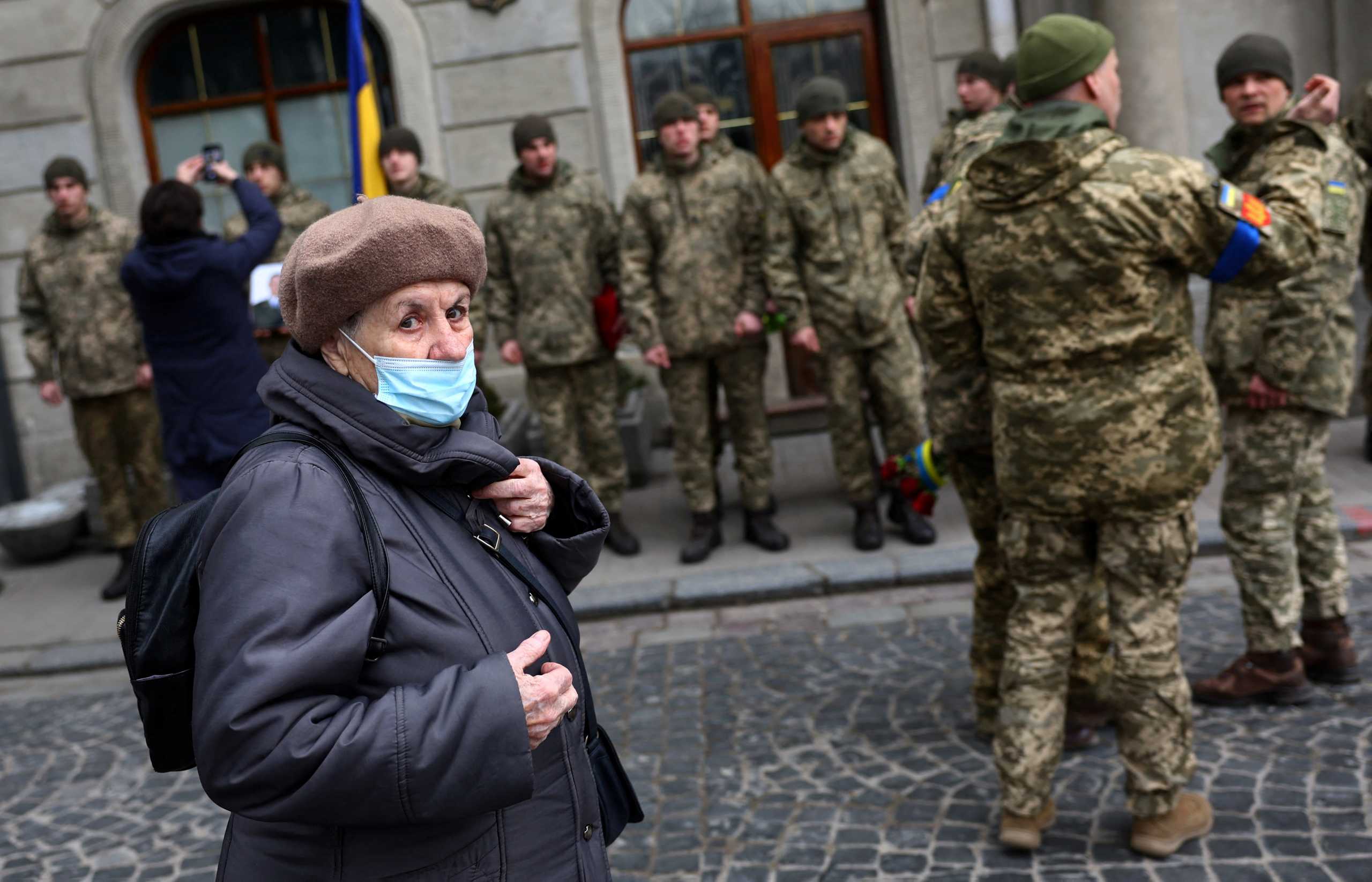 An elderly woman walks past an honour guard waiting for the funeral procession of Eduard Niezhenets, who was killed in a rocket attack against a military base in Yavoriv during the ongoing Russian invasion, prior to his memorial service at the Saints Peter and Paul Garrison Church in Lviv, Ukraine, March 16, 2022.  REUTERS