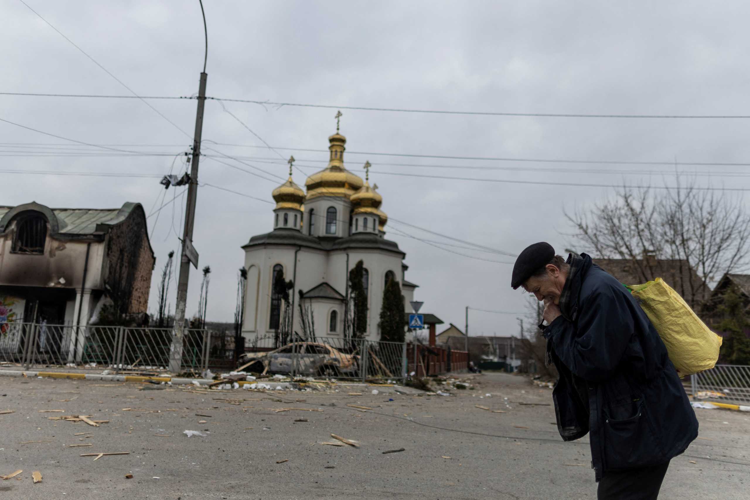 A man takes a pause as he evacuates from the town, on the only escape route used by locals after days of heavy shelling, while Russian troops advance towards the capital, in Irpin, near Kyiv, Ukraine March 7, 2022. REUTERS