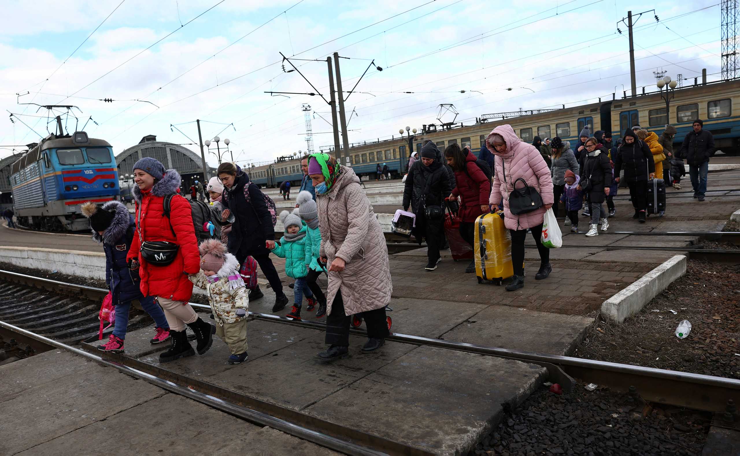 Refugees fleeing the ongoing Russian invasion of Ukraine cross the tracks after arriving on a train from Kyiv region at the train station in Lviv, Ukraine, March 8, 2022. REUTERS