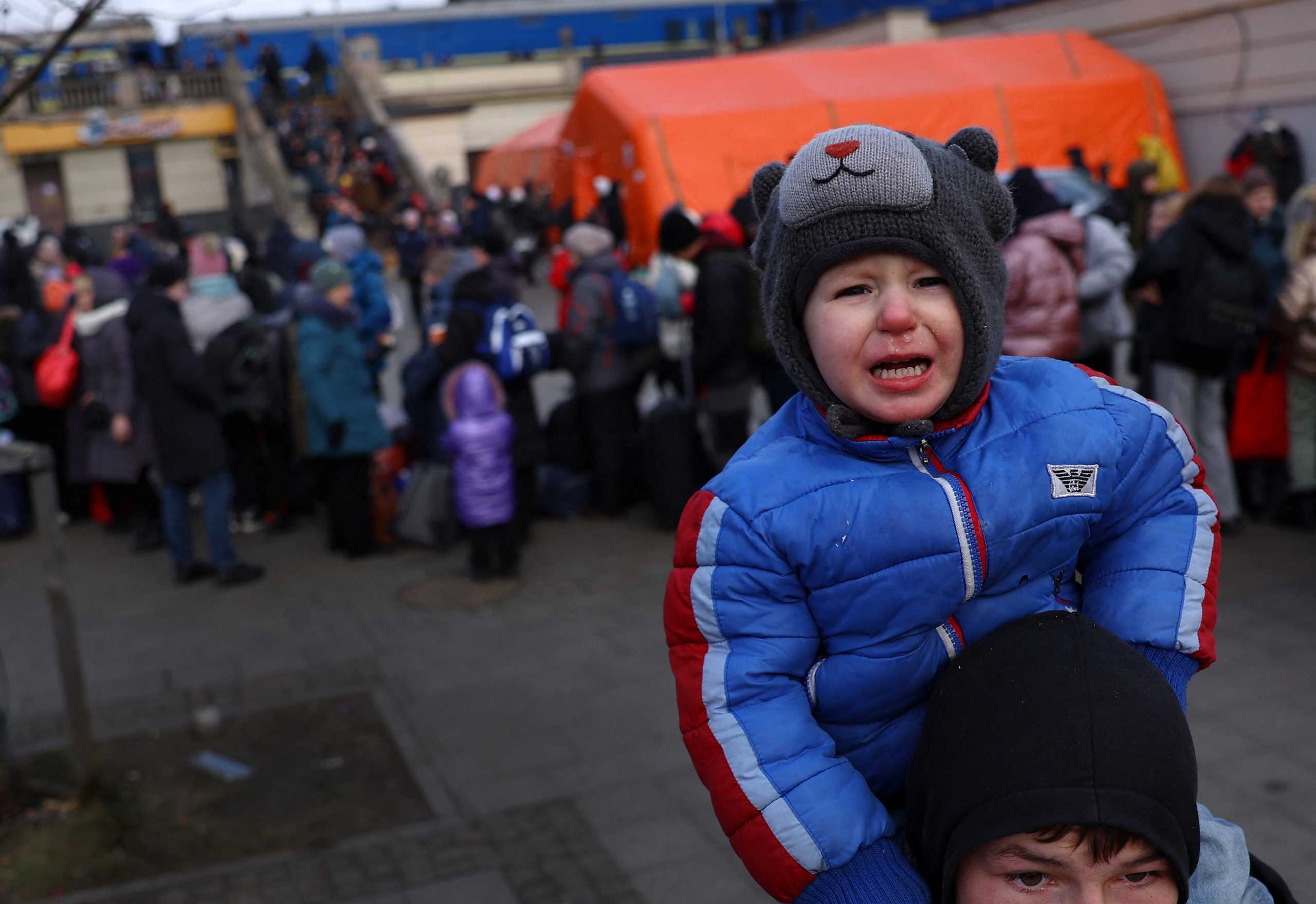 A young boy cries sitting on the shoulders of his brother as they search for their mother after fleeing the ongoing Russian invasion of Ukraine, outside the train station in Lviv, Ukraine, March 8, 2022. REUTERS