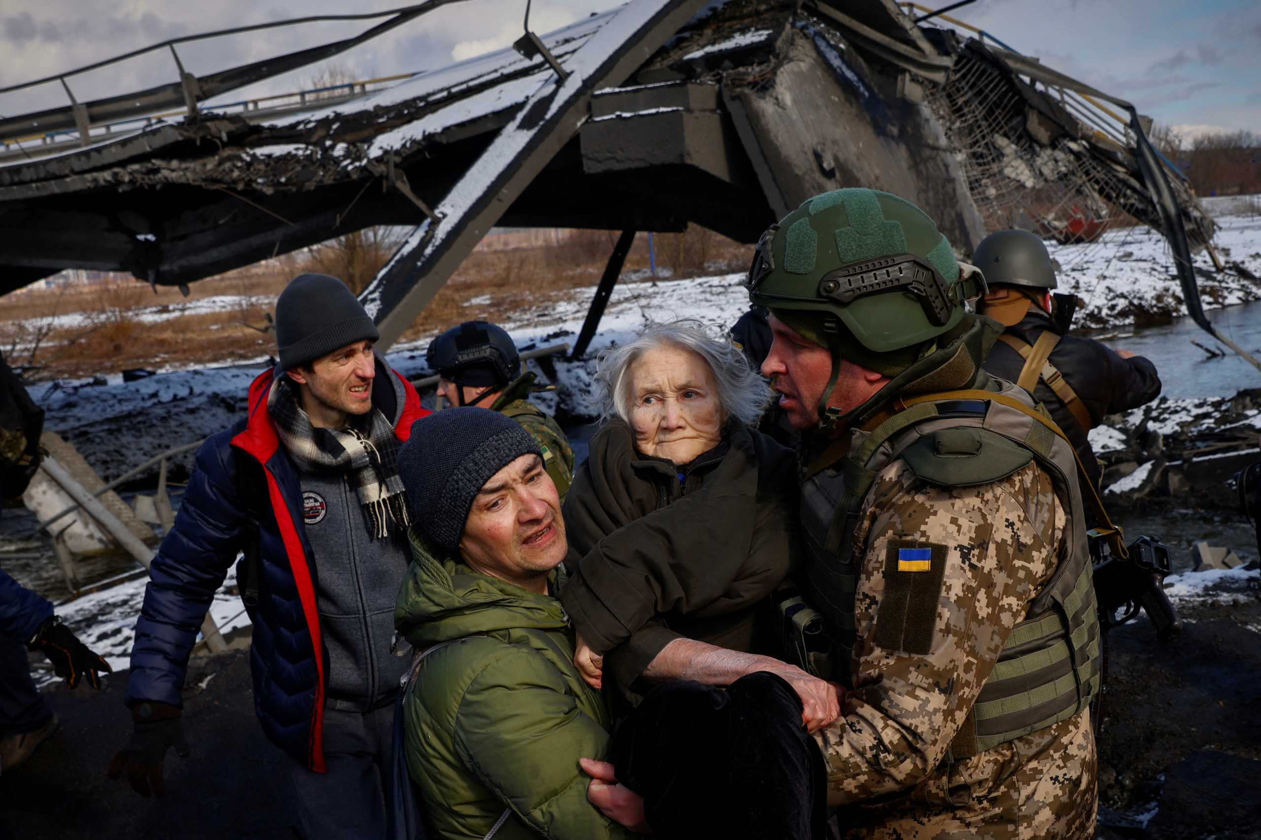 Two men carry a woman as people flee from advancing Russian troops whose attack on Ukraine continues in the town of Irpin outside Kyiv, Ukraine, March 8, 2022. REUTERS